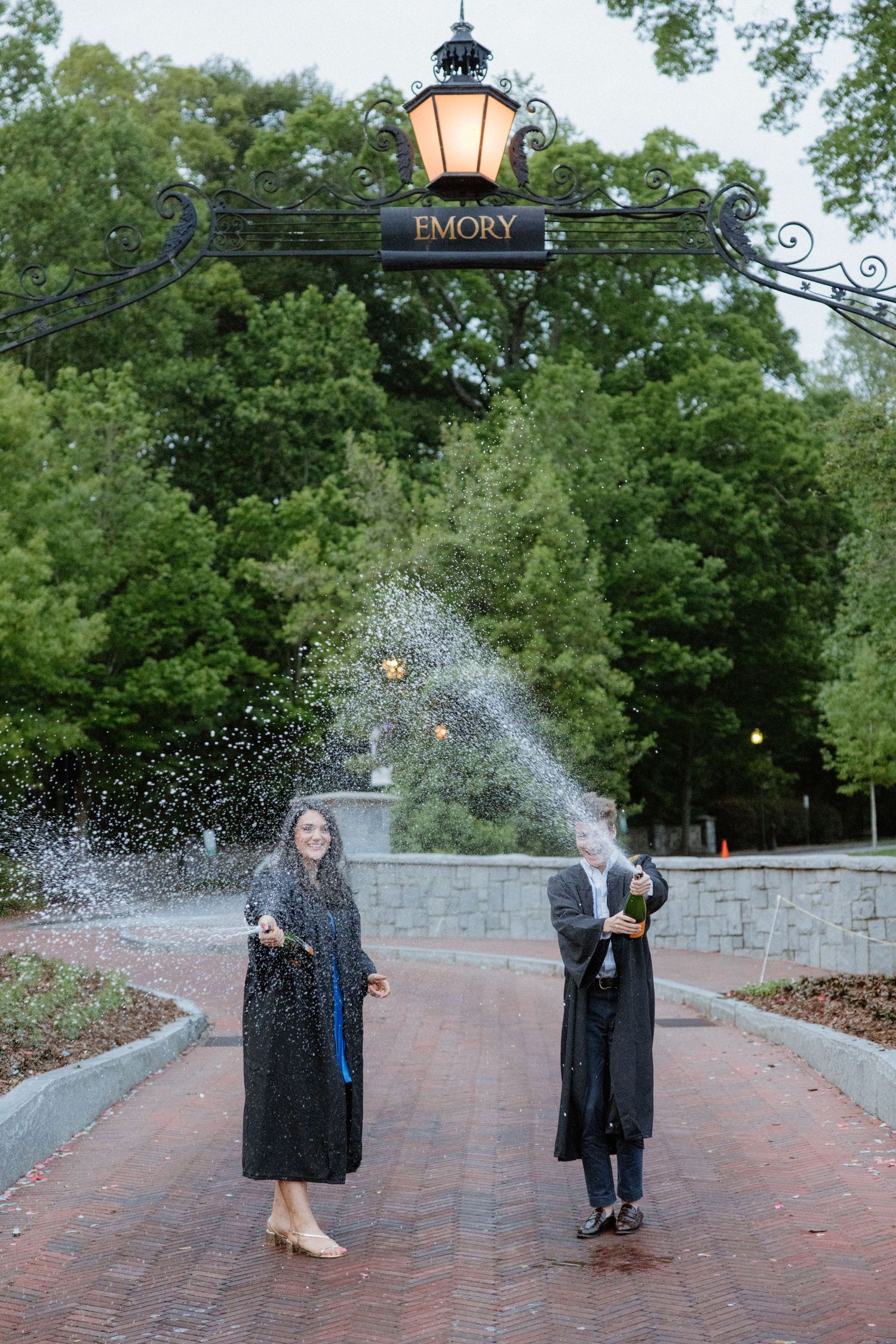 Graduates in caps and gowns create splashing water effects during a photo session at Emory University.