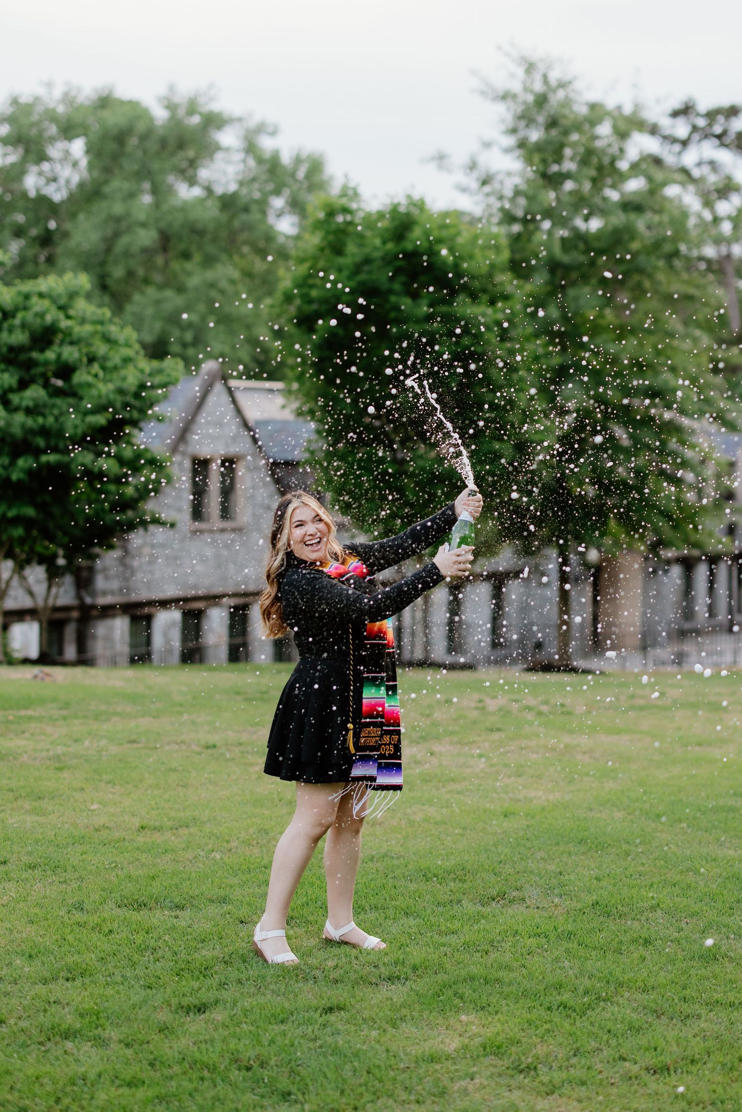 A sequence of photos shows someone joyfully tossing white flower petals in the air on a grassy lawn near stone buildings.