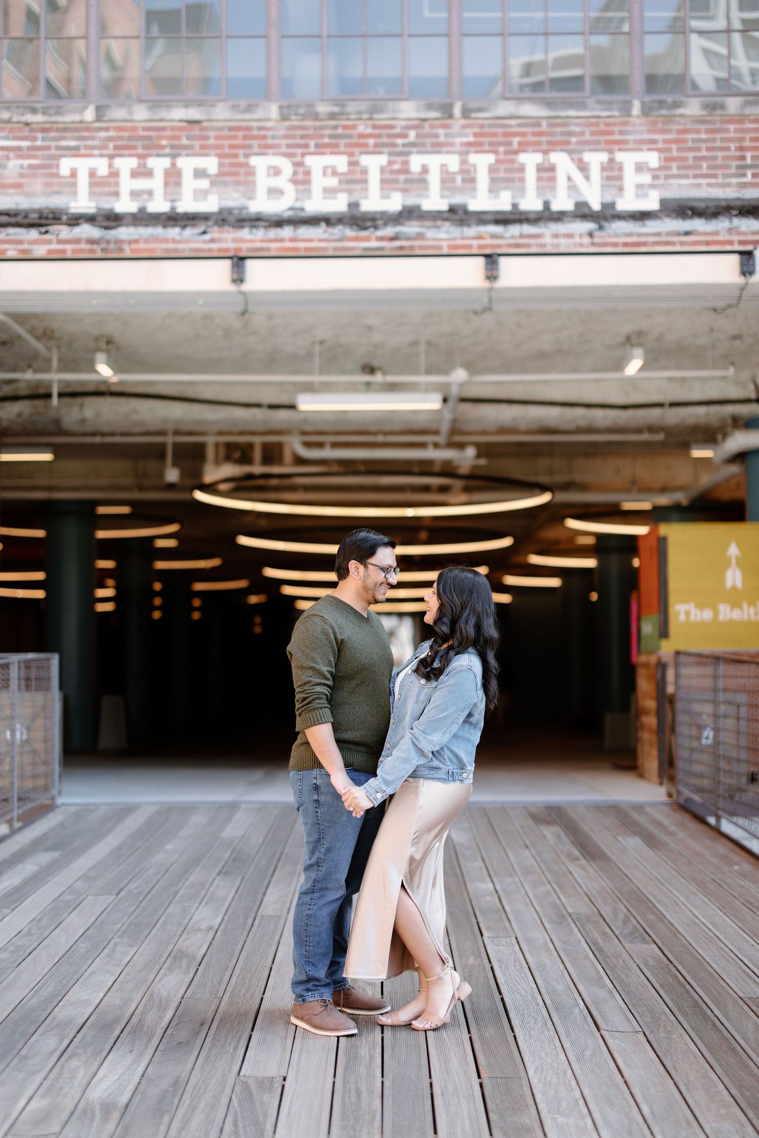 A couple shares an intimate moment on a wooden boardwalk at The Beltline, creating a romantic composition.