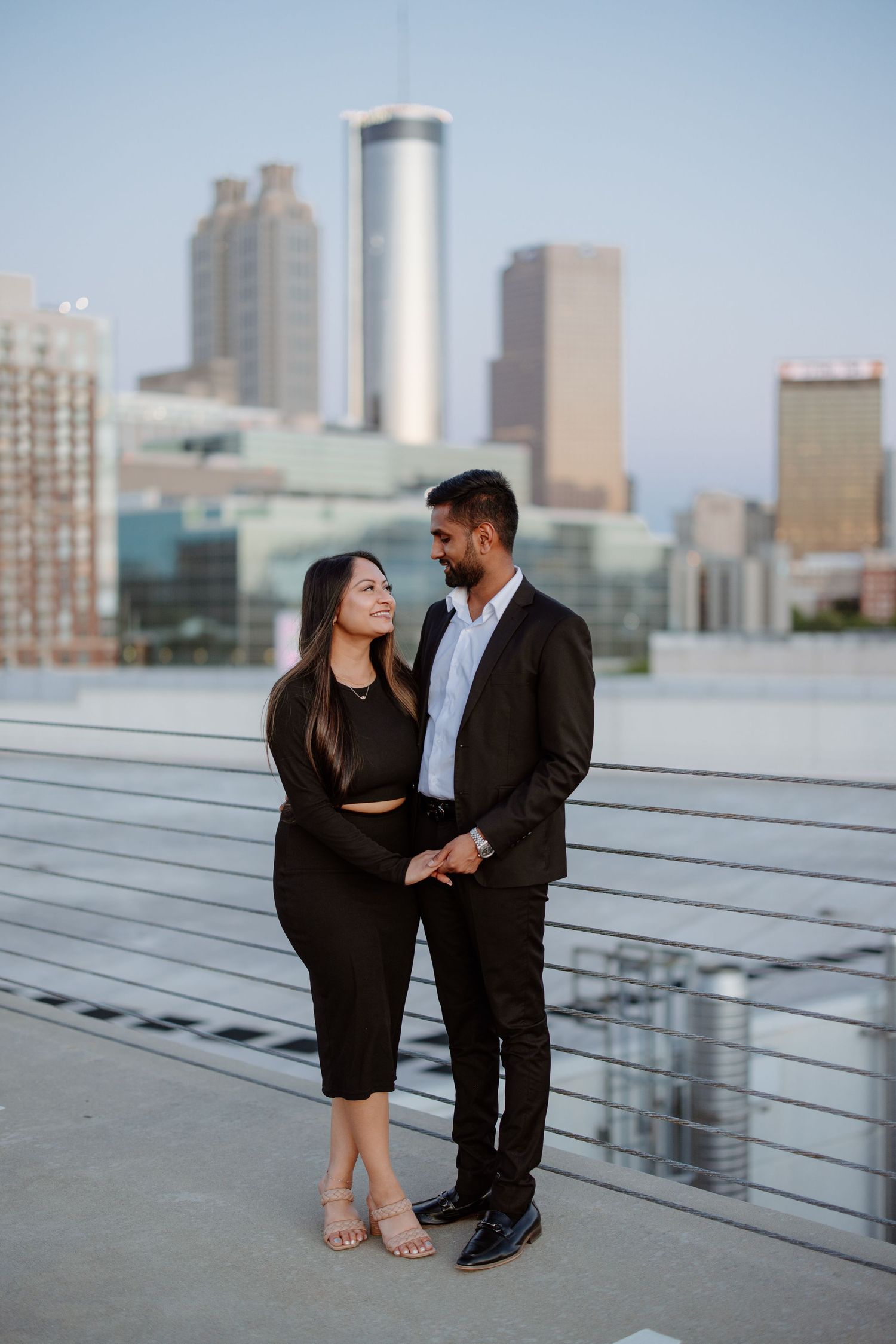 Urban rooftop photoshoot with city skyline in background at dusk.