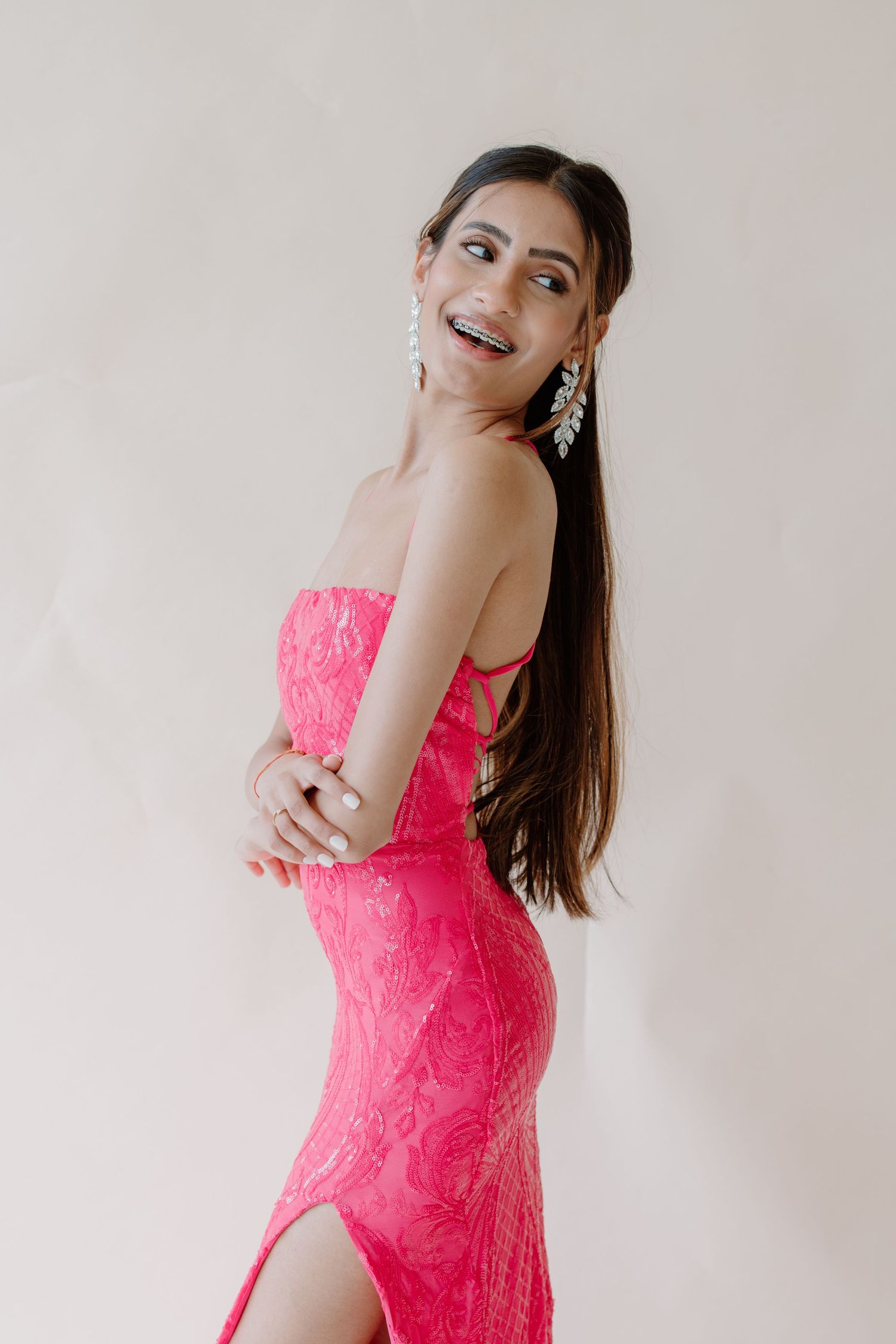 A fashion photo sequence showing someone posing in a bright coral pink lace dress against a light background.