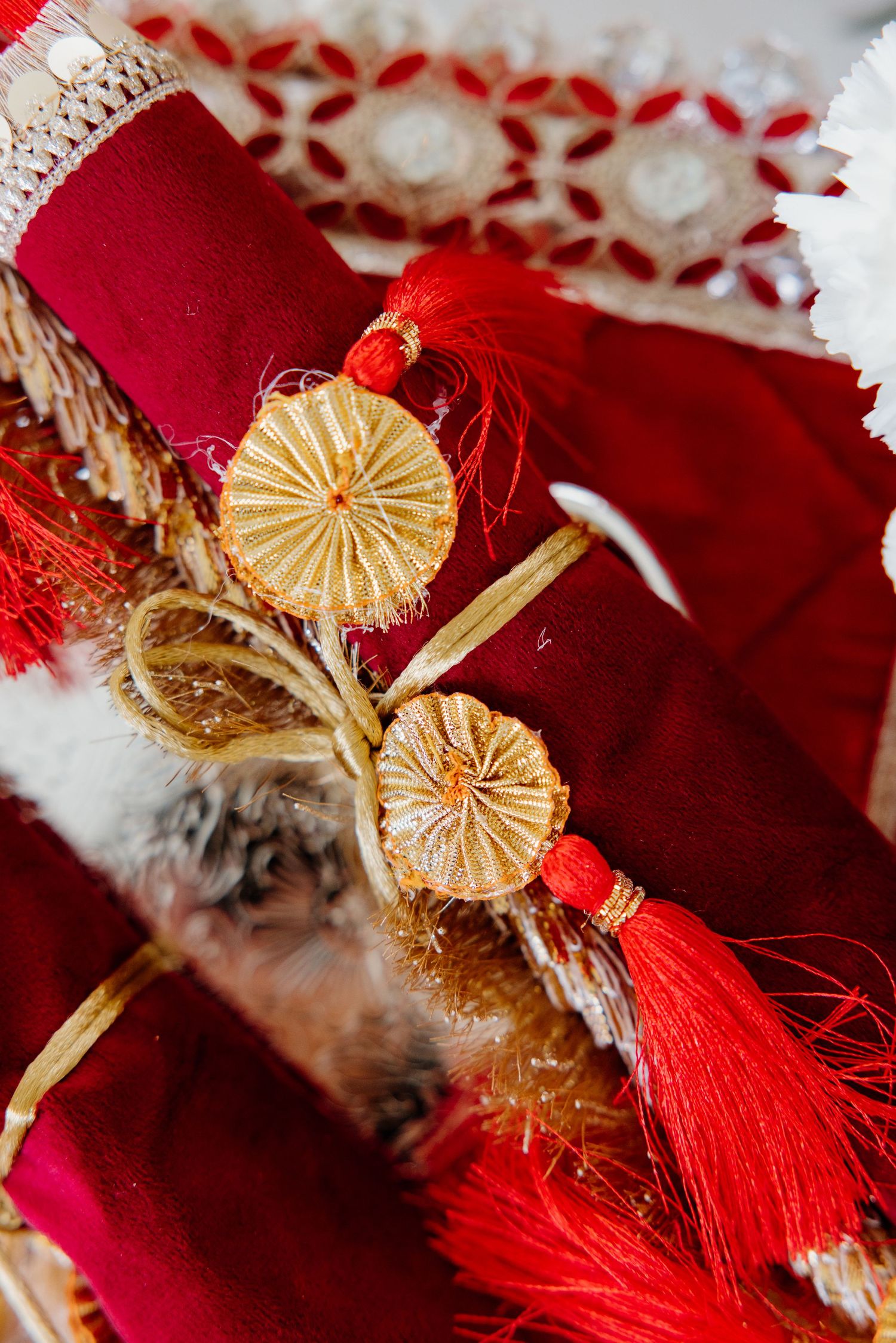 Close-up details of Christmas decorations featuring delicate gold paper fans and bright red tassels against crimson fabric.