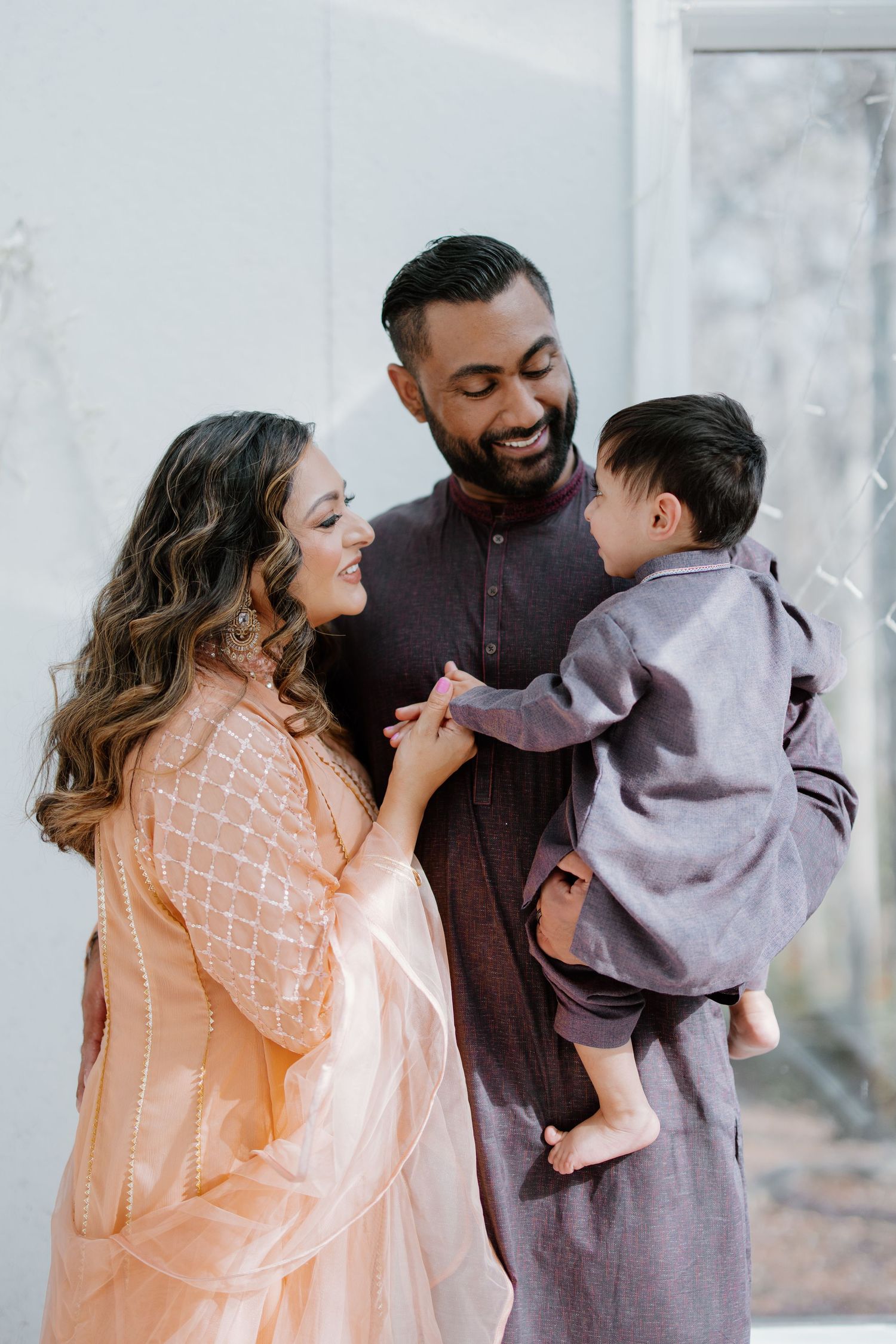 A loving family shares a tender moment together outdoors, wearing traditional South Asian inspired outfits.
