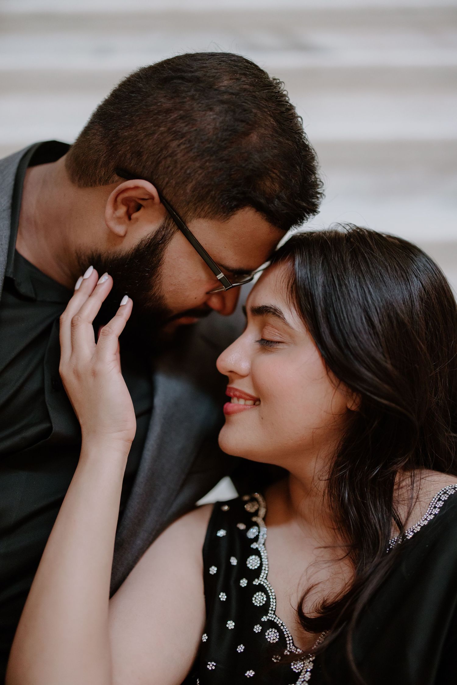 Romantic close-up of a couple in black attire sharing an intimate moment with tender expressions.