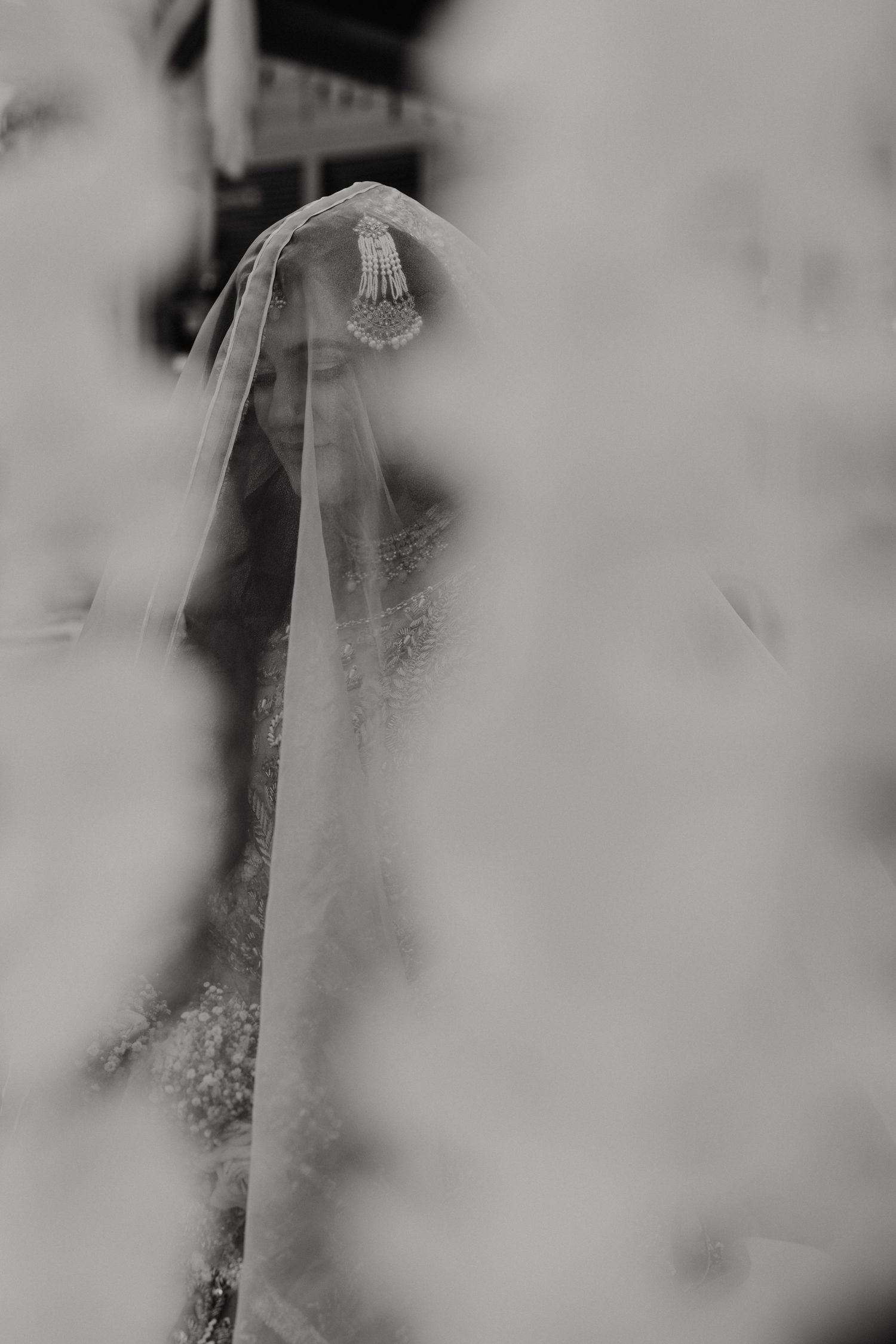 A soft and romantic black and white bridal portrait with a delicate veil creating a dreamy ethereal effect.