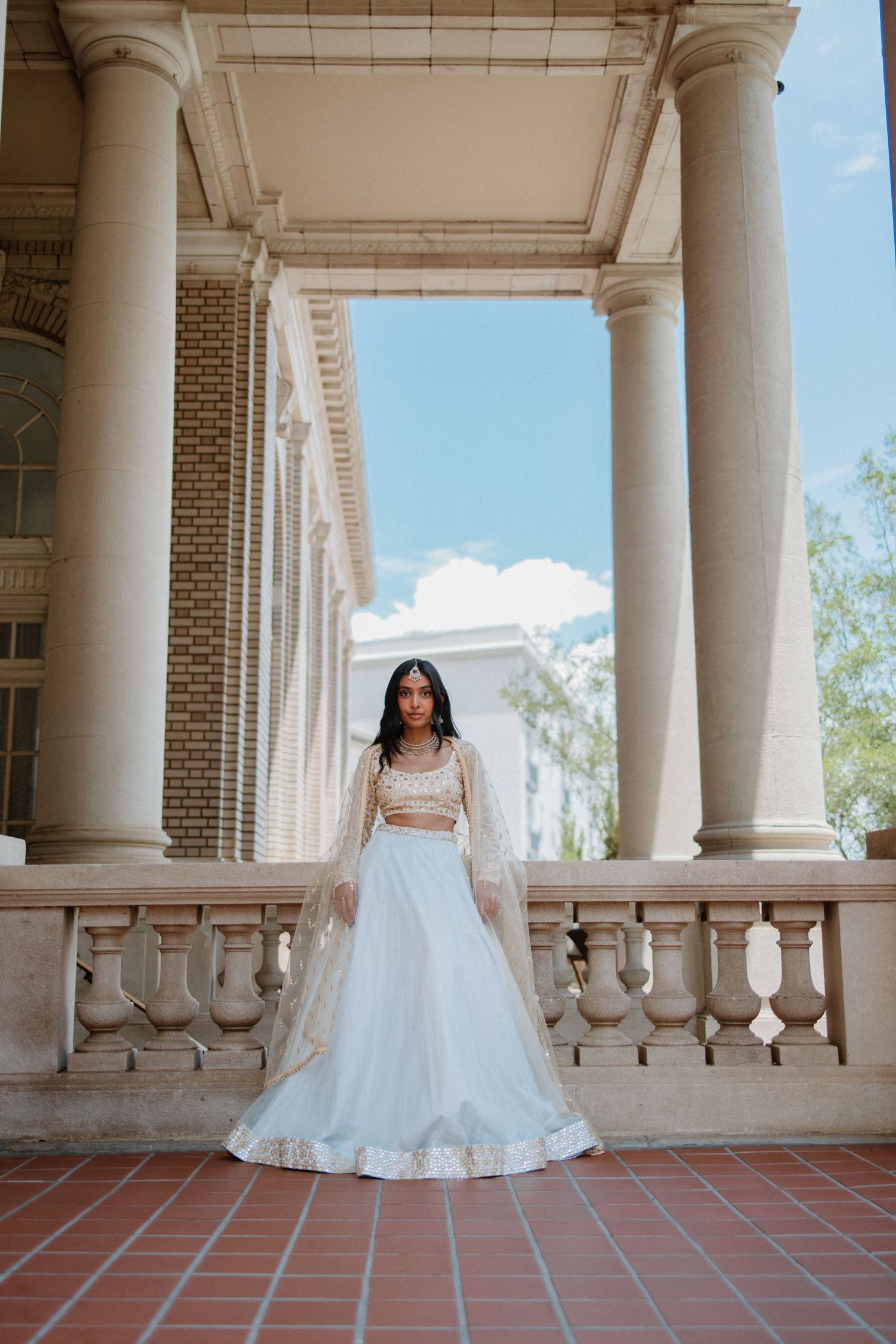 A series of elegant bridal photos captured under a columned portico with brick and stone architectural details.