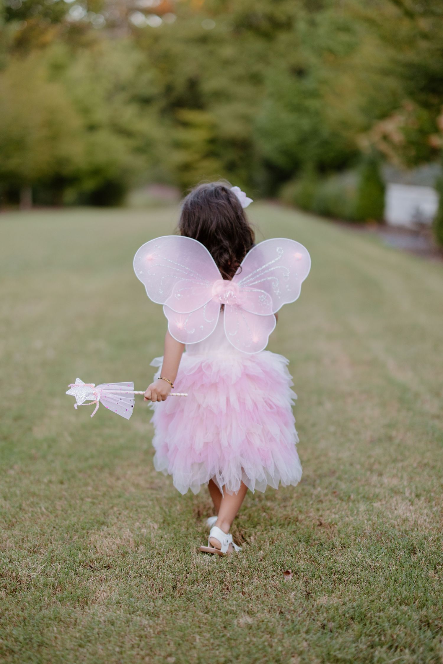 A young pink fairy with tulle wings in a dreamy garden photo session sequence.