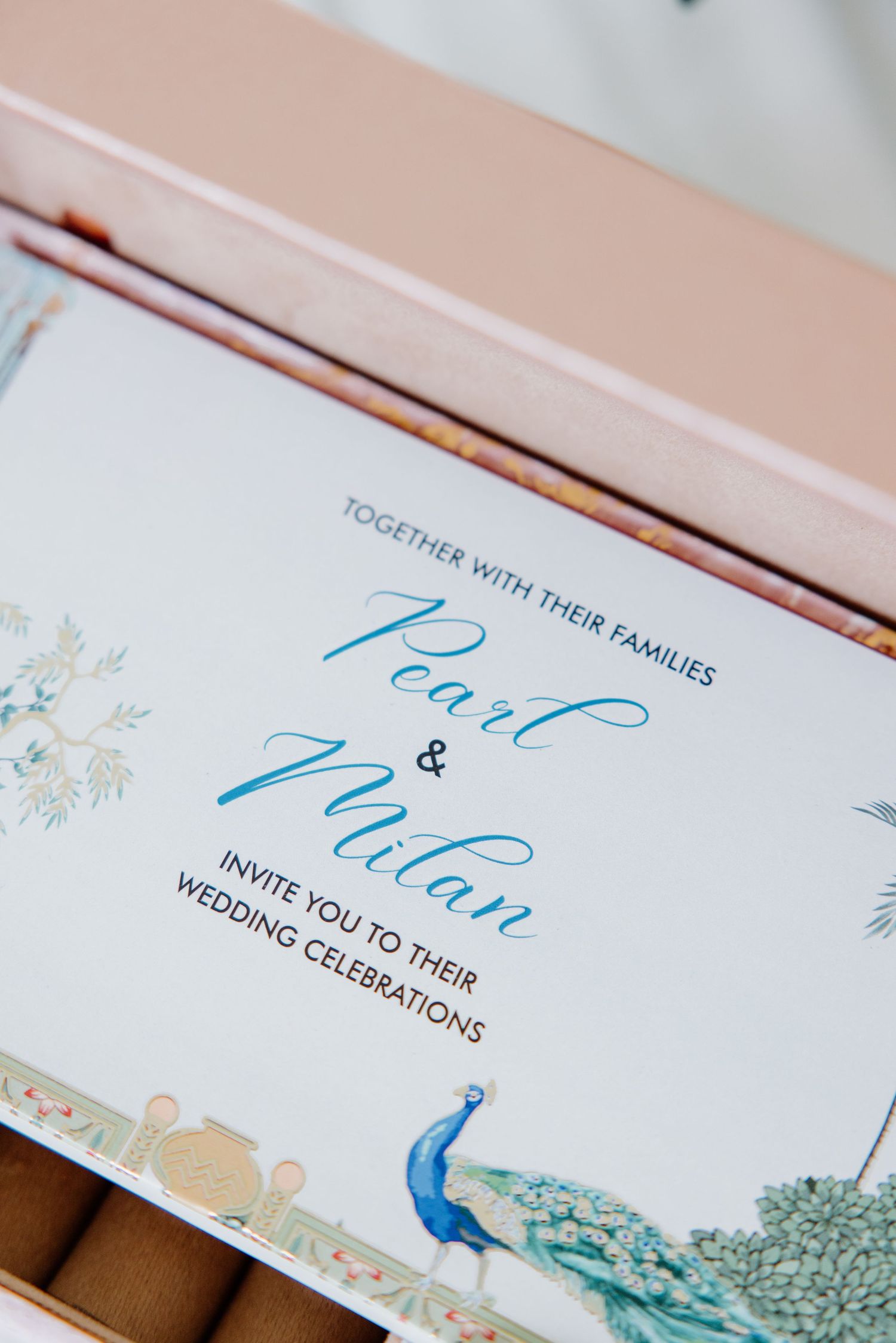 Closeup of elegant wedding invitations with blue calligraphy text and delicate floral designs.