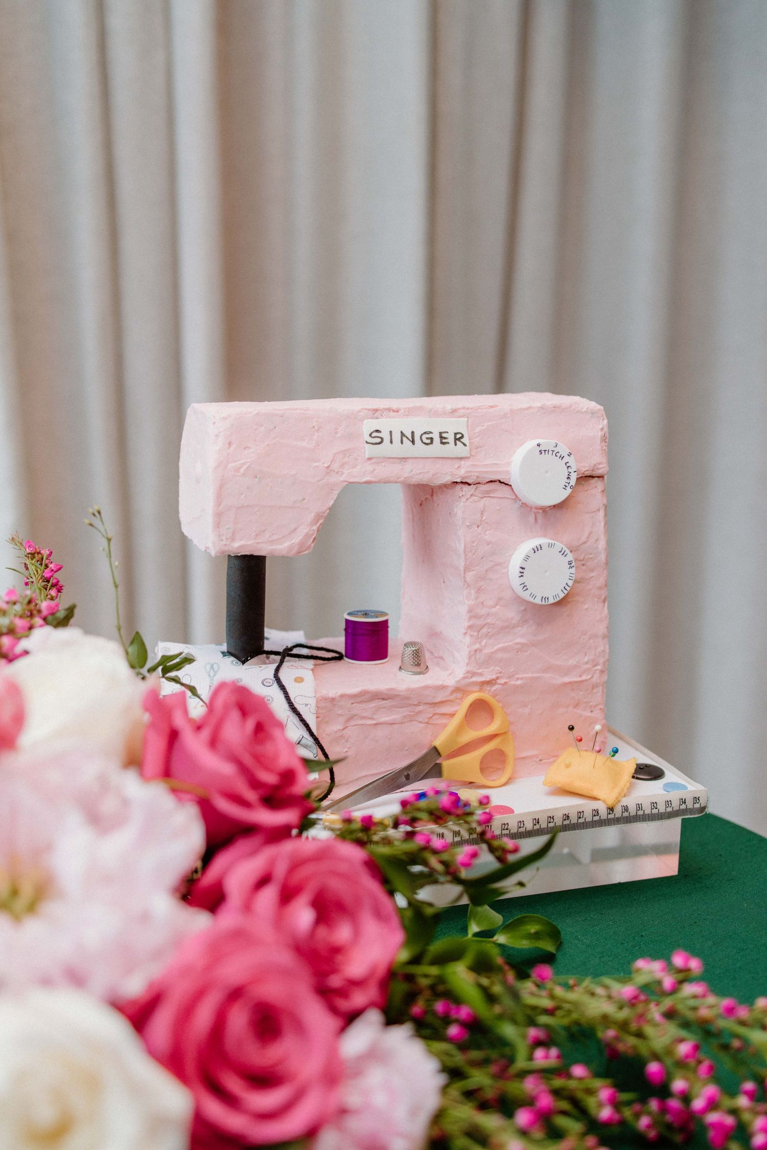 Pink vintage Singer sewing machine with roses and floral decorations against a blurred background.