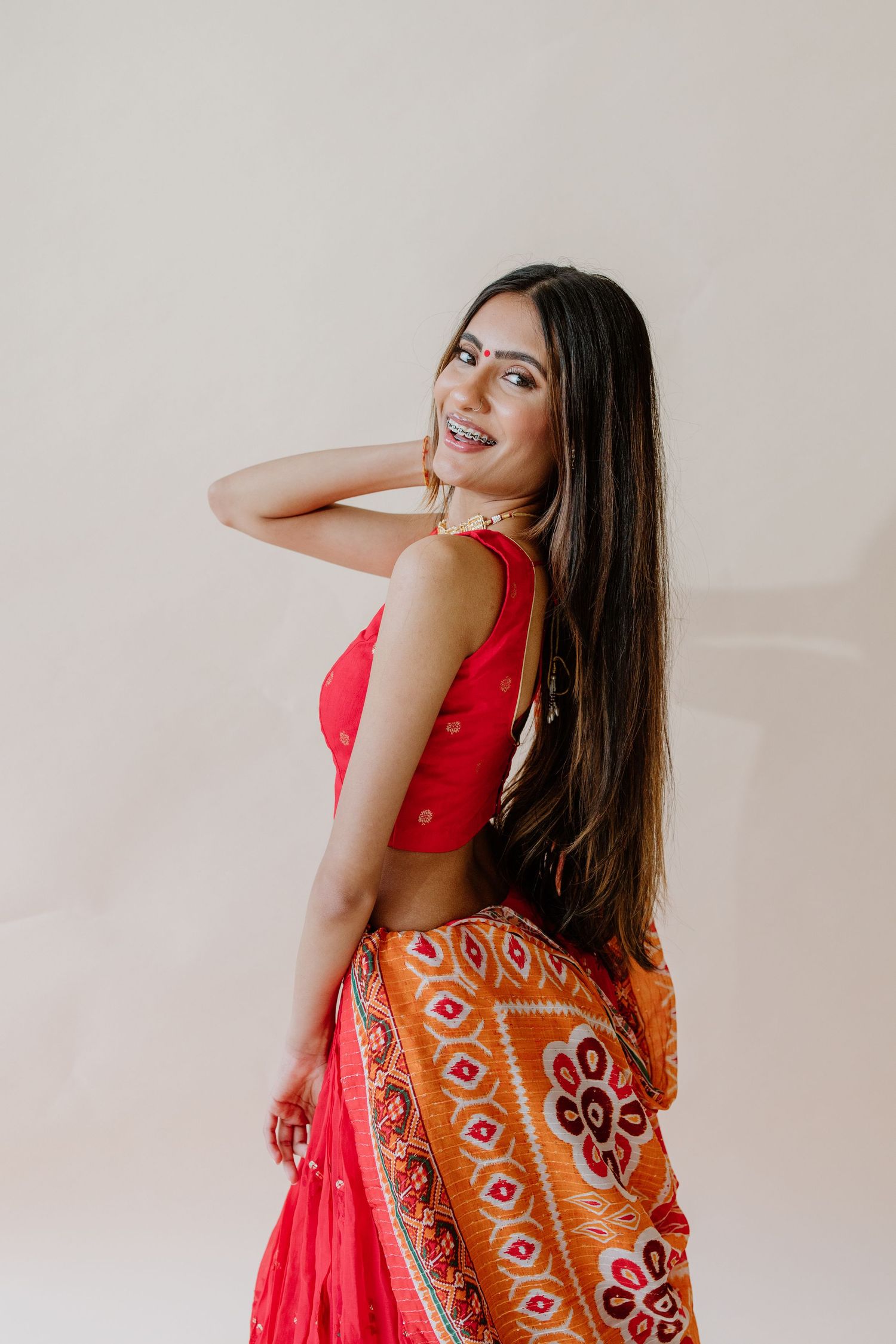 A series of photos showing a person in a bright red dress with traditional Indian embroidered details, captured against a light backdrop.