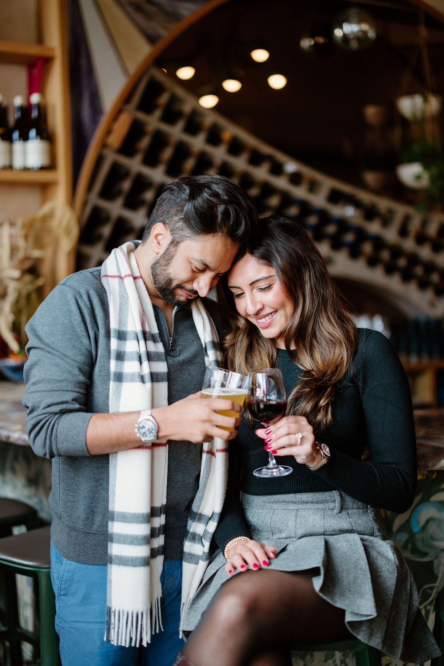 A couple laughs and shares wine while enjoying an intimate moment at a restaurant.