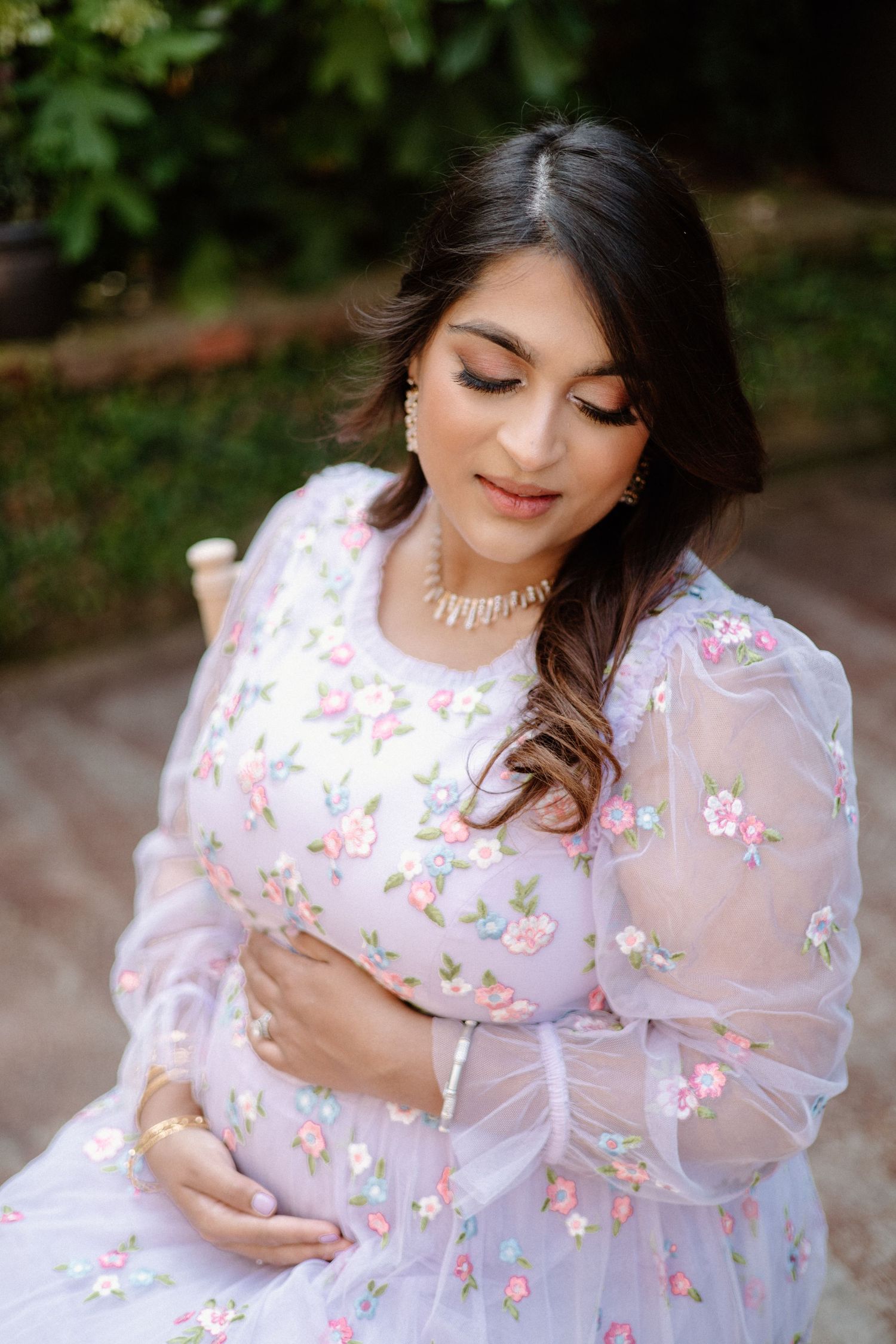 A feminine figure in a white floral dress with puff sleeves poses gracefully in a nature-inspired photoshoot.