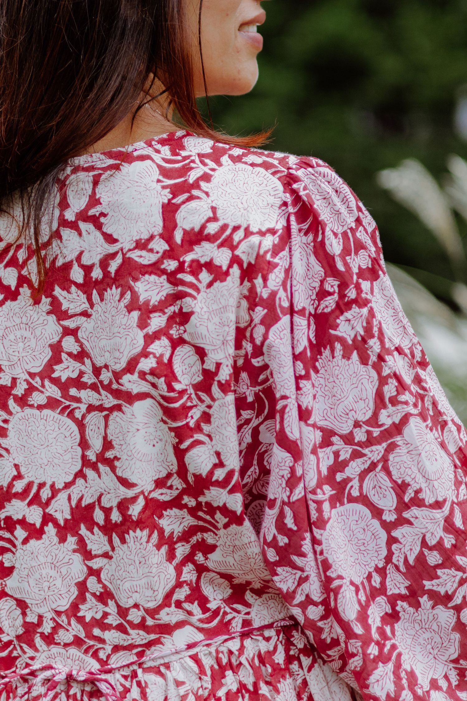 Closeup shots of red and white floral pattern fabric details on a garment with ornate scrollwork designs.