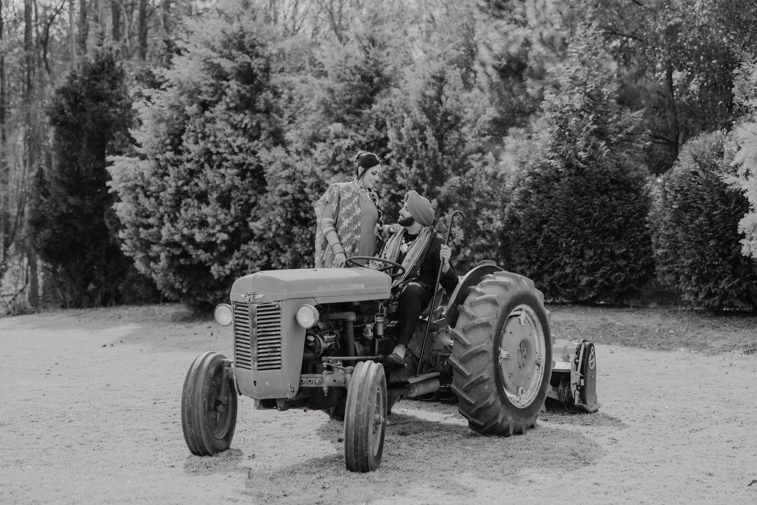Series of vintage John Deere tractors on display in a rural outdoor setting with trees in the background.