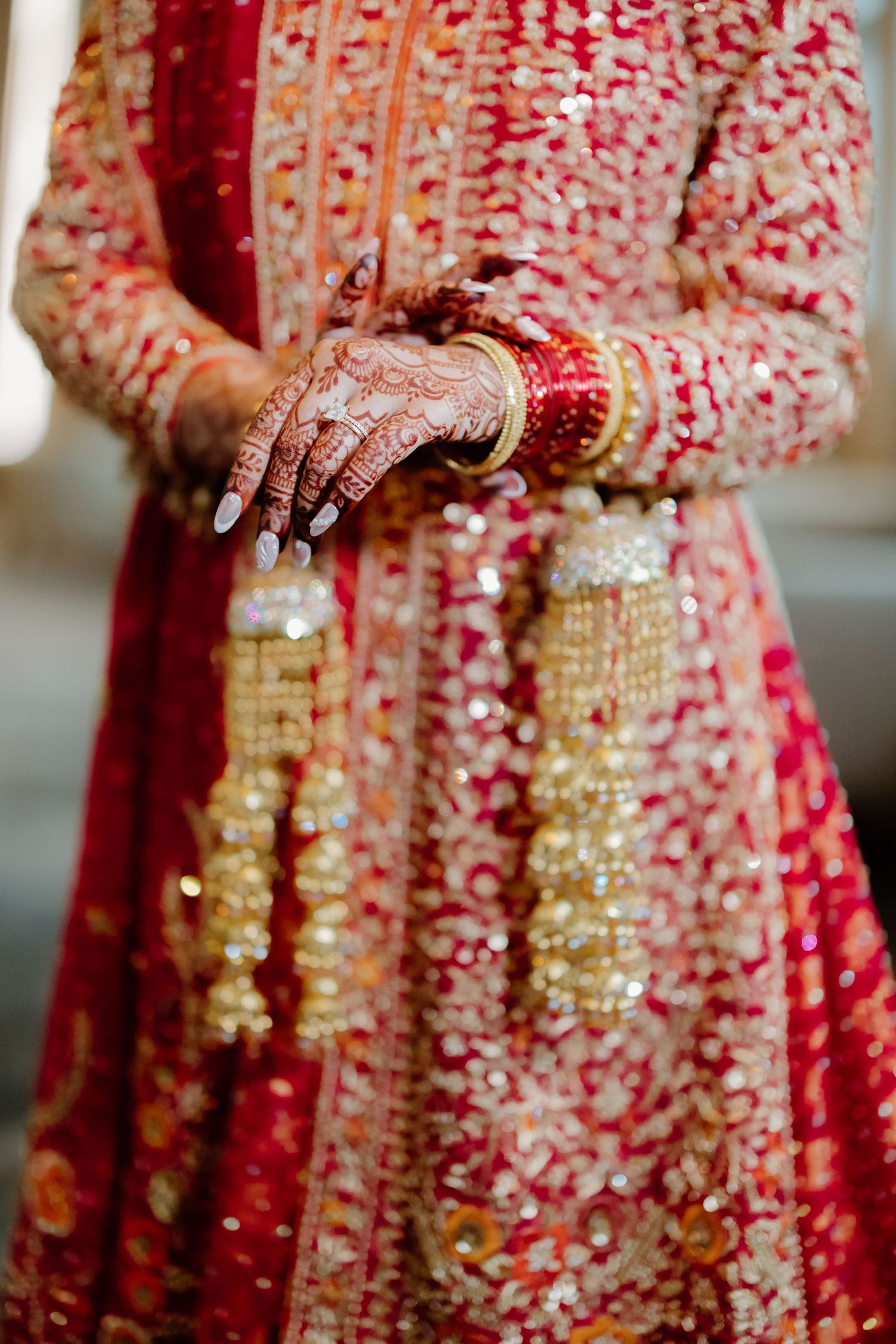 Detailed view of ornate red and gold traditional South Asian wedding dress with intricate embellishments.