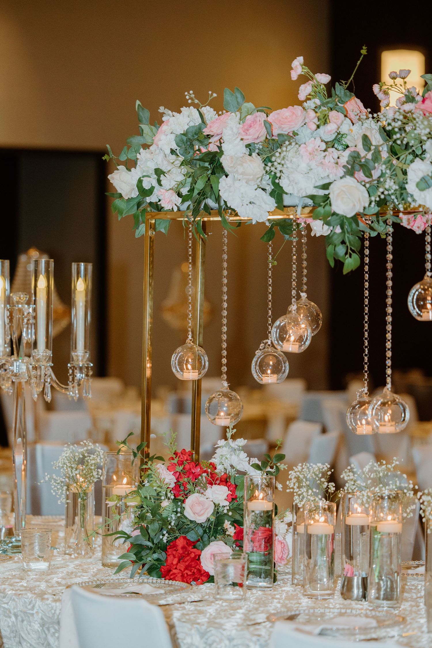 Elegant wedding table centerpiece with suspended glass orbs and pink and white floral arrangements on white tablecloth.