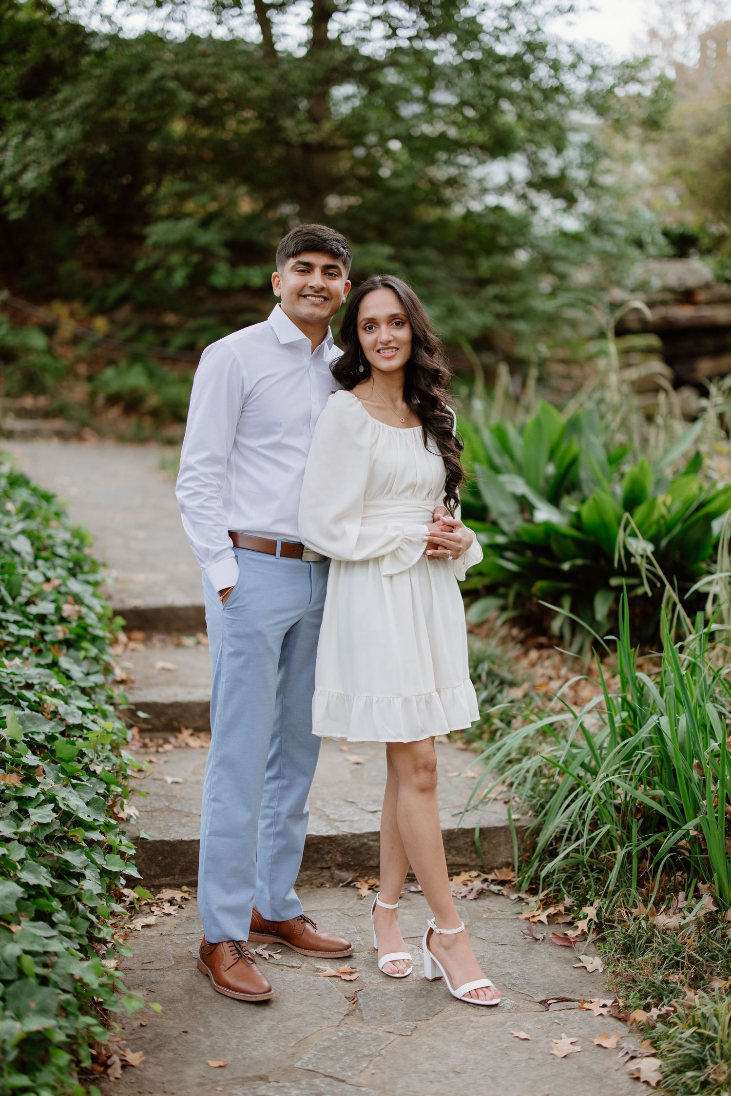 Close-up details of footwear and dress hems as two people stand together in a garden path setting.