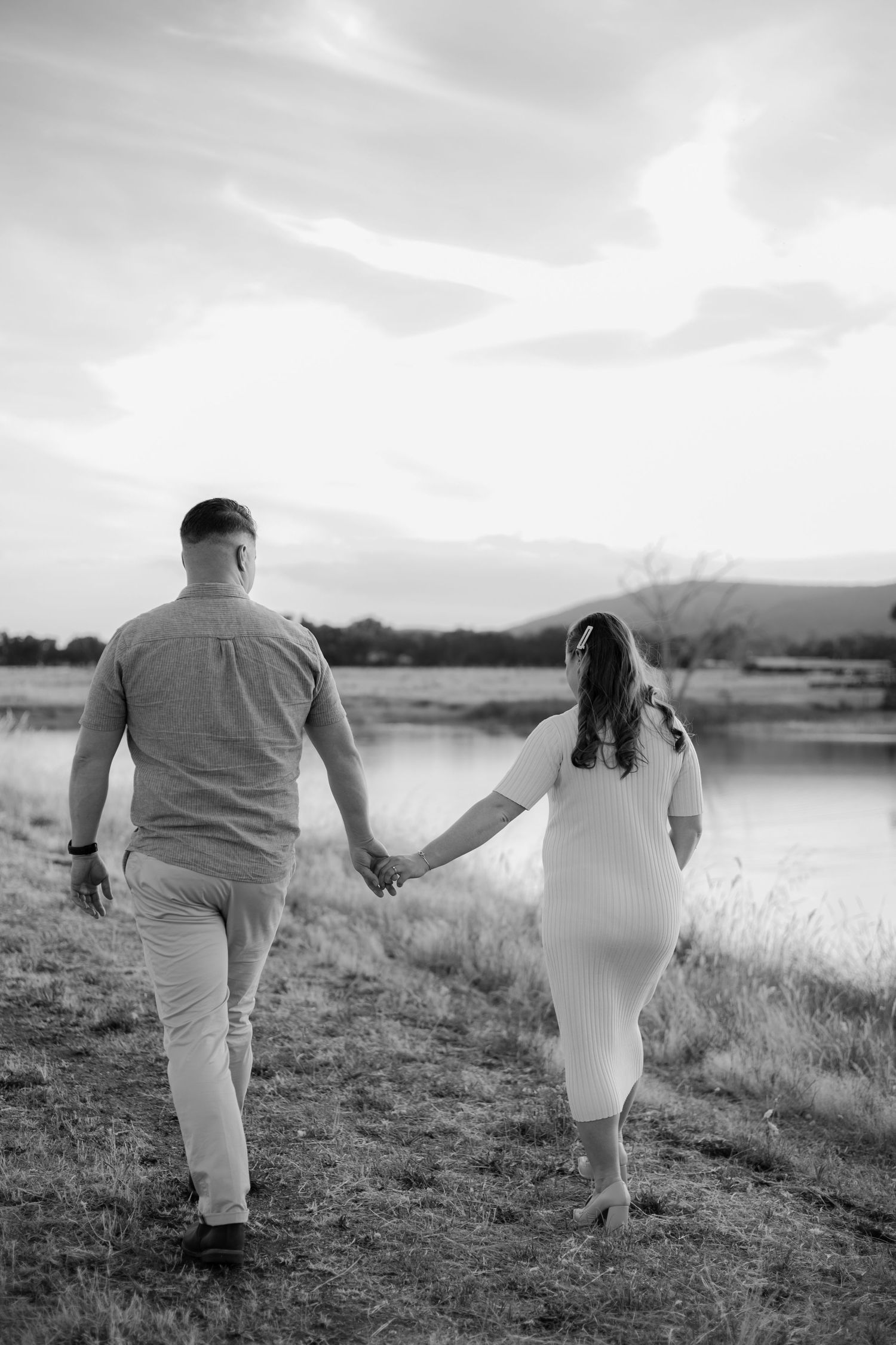 A black and white photo sequence shows a couple holding hands walking along a lakeside path at sunset.