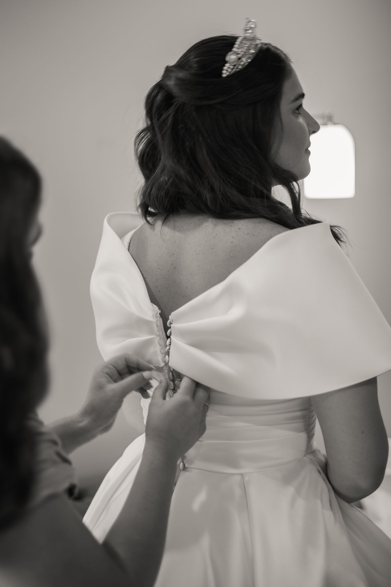 Monochromatic series showing dress fitting detail of adjusting a white gown's dramatic collar.