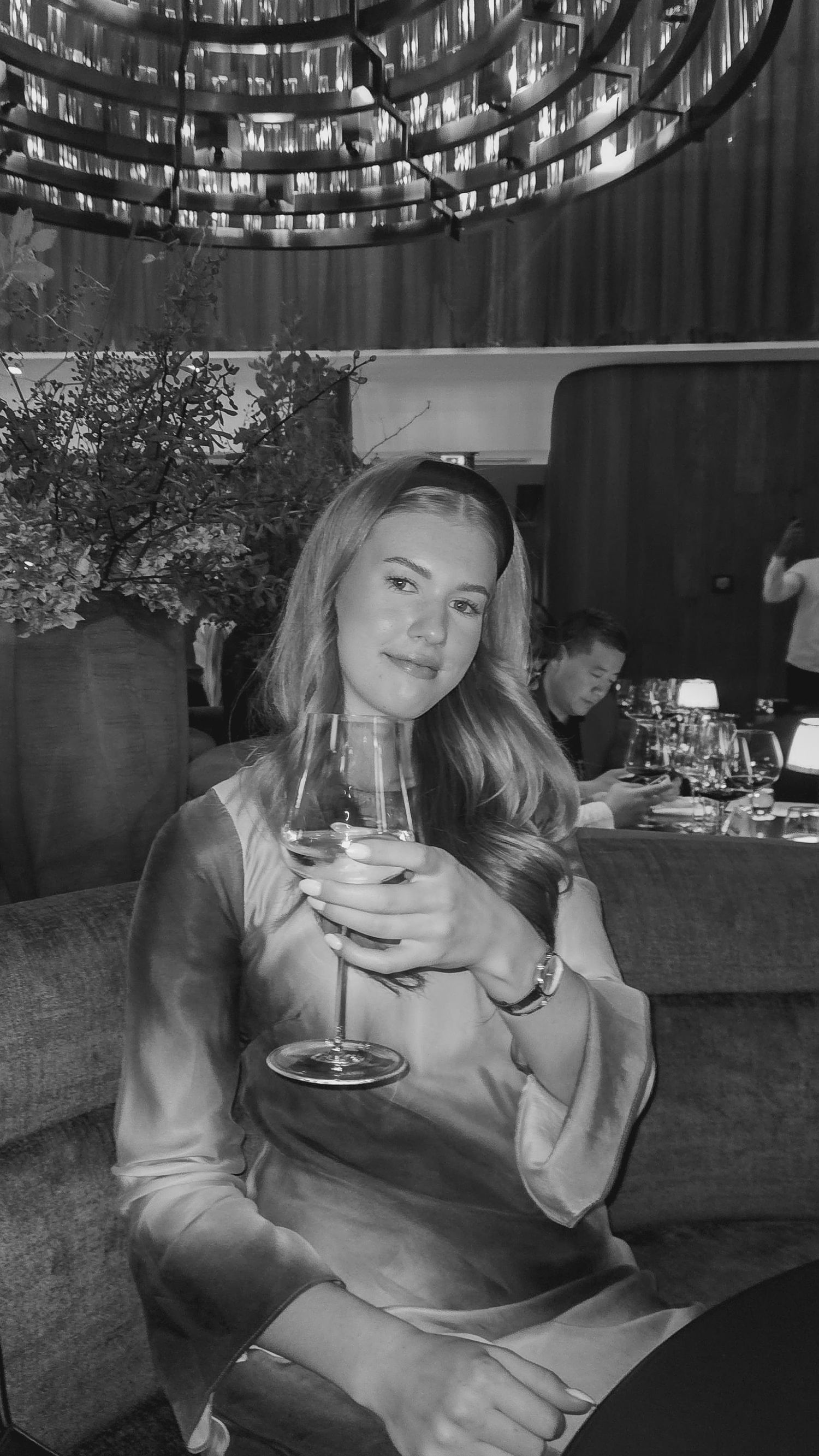 A person enjoys cocktails at a dimly lit restaurant with elegant lighting and dark ambiance.