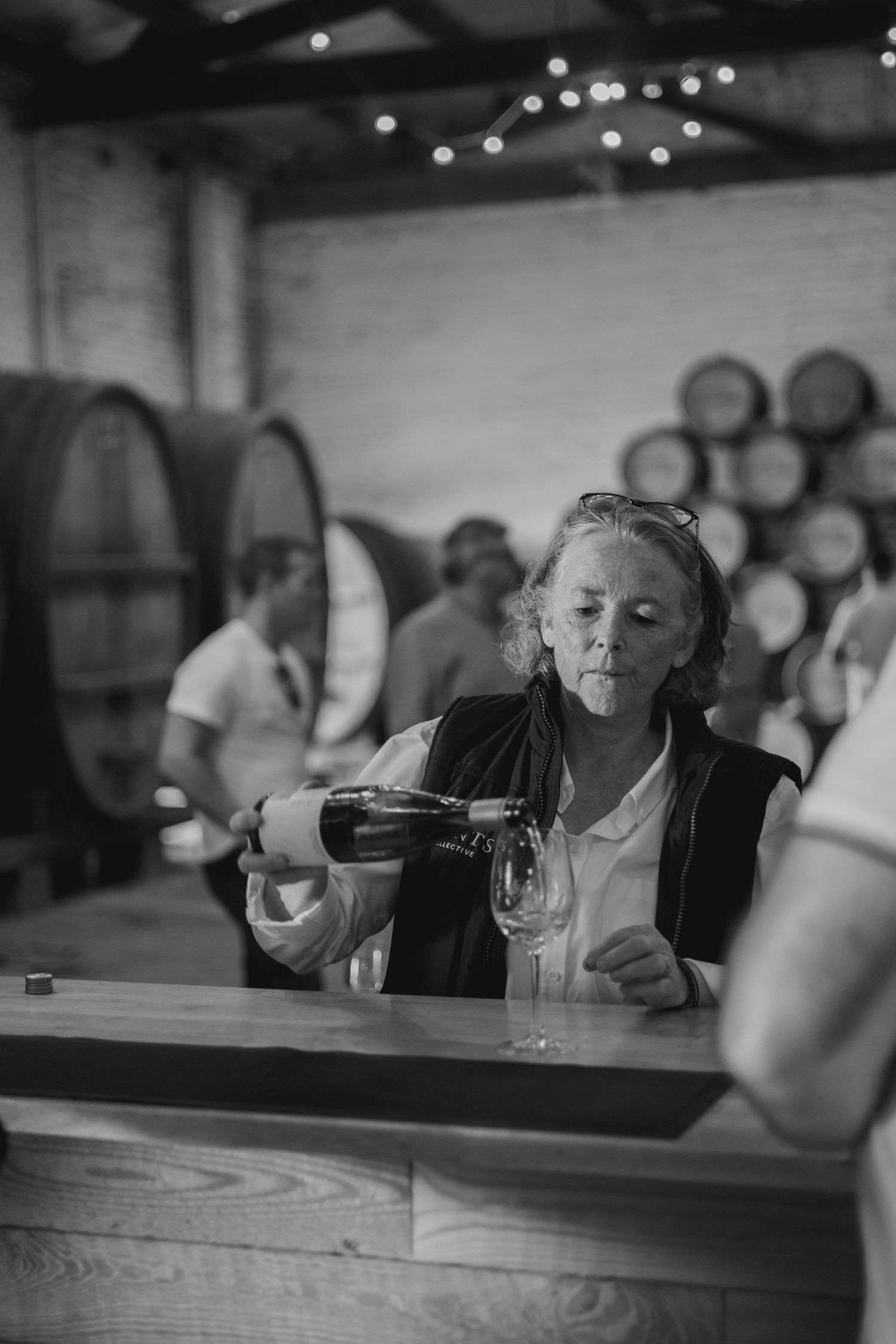 A wine pouring session in a rustic cellar with wooden barrels and ambient lighting in the background.