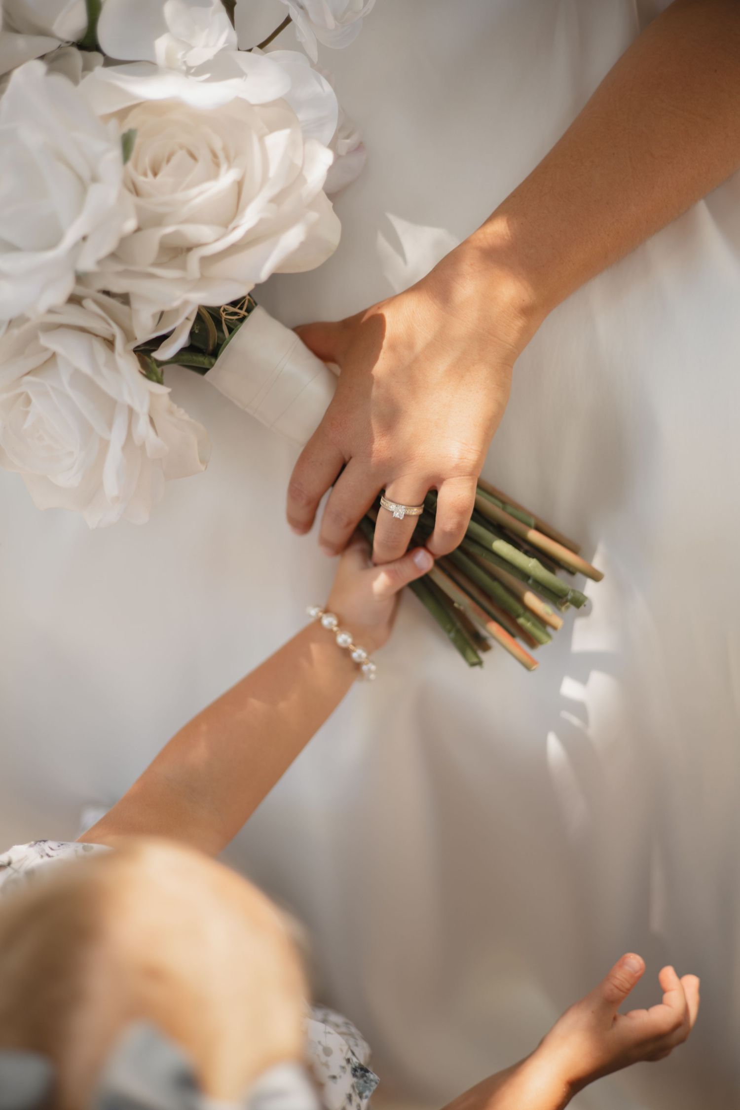 Elegant close-up shots of hands with pearl bracelet and wedding ring holding a delicate white floral bouquet.