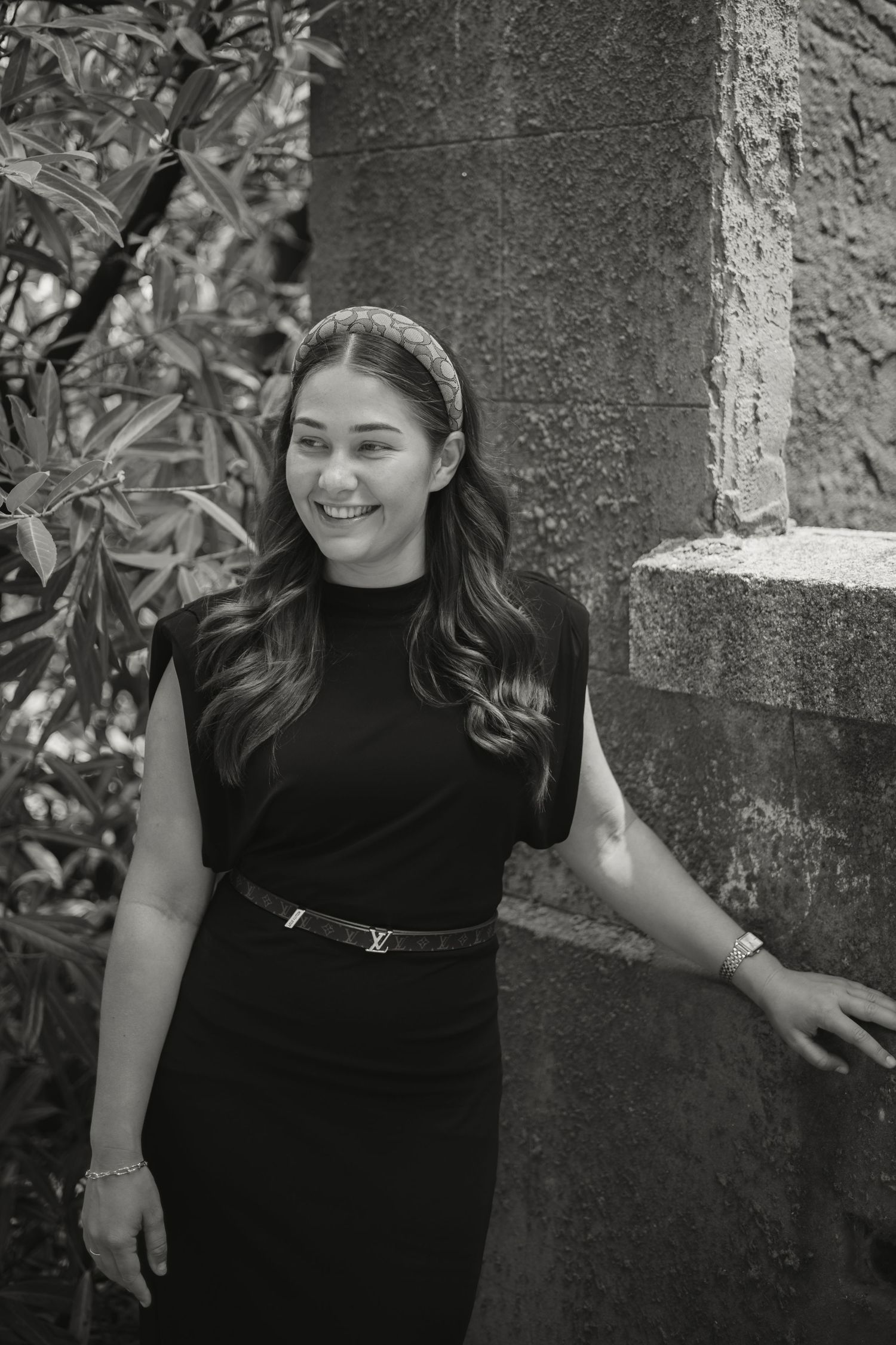 A sequence of black and white photos showing someone in a black top posing against a stone wall outdoors.