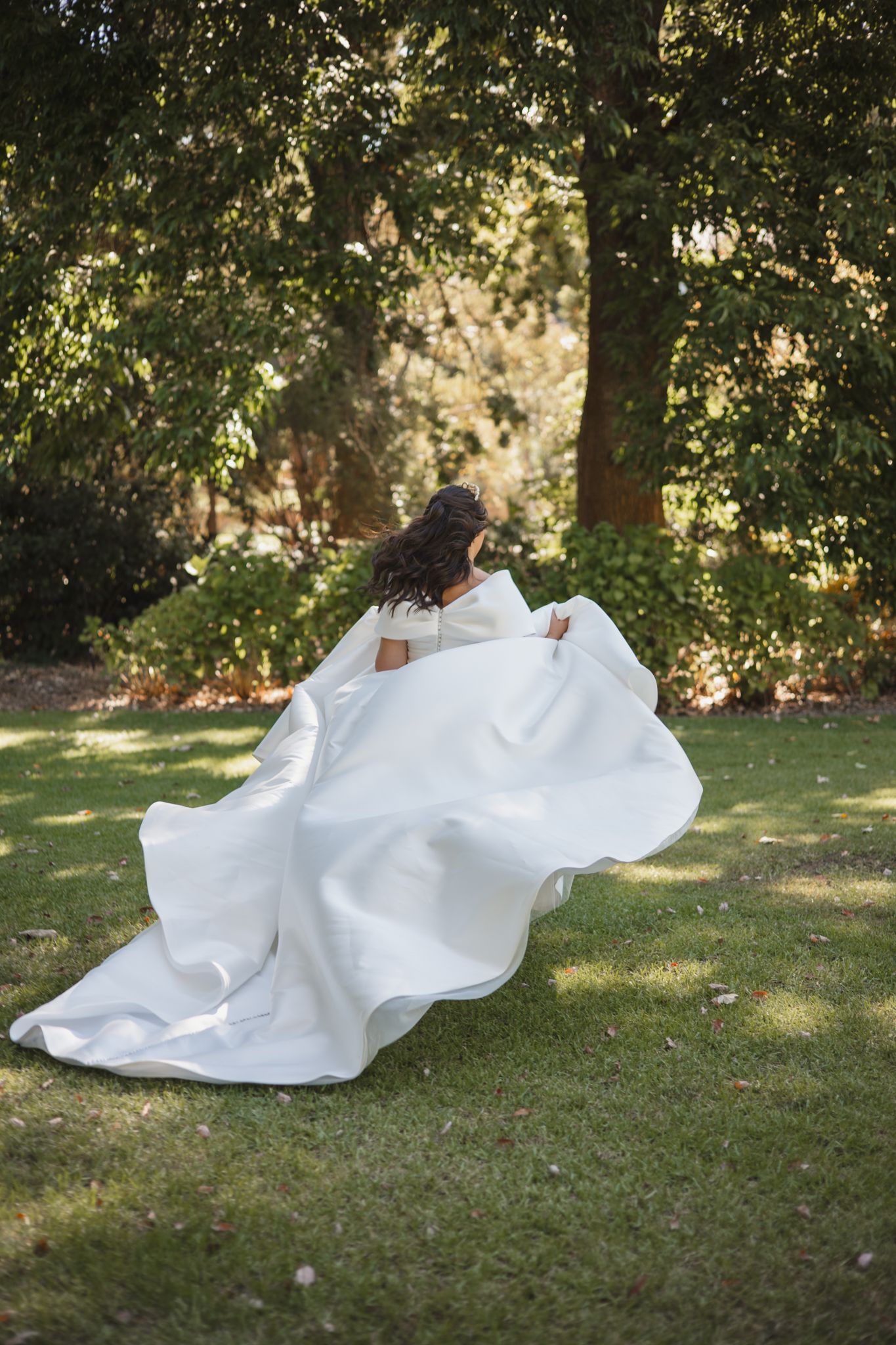 A flowing white wedding dress billows gracefully across green grass in a series of artistic outdoor photos.