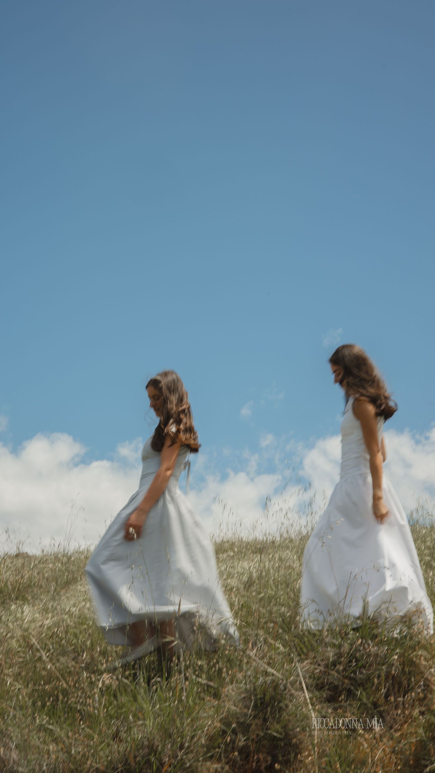 Two girls walking through the grass.