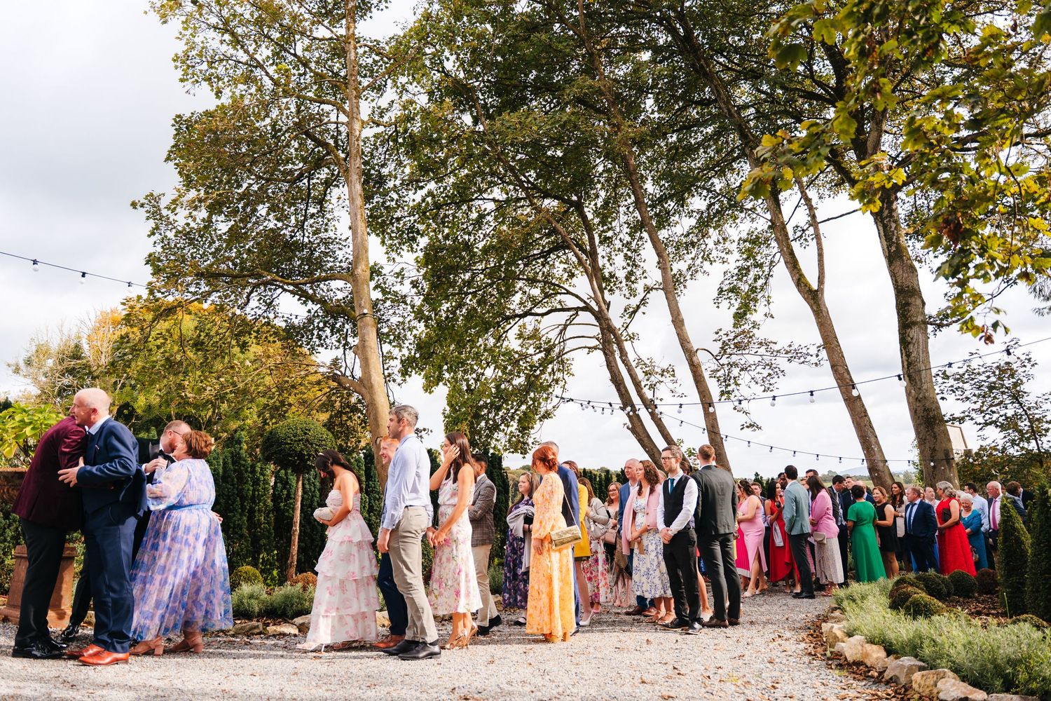 Wedding guests gather outdoors under tall birch trees during an autumn ceremony. LGBTQ Ashley Park Wedding Photographer