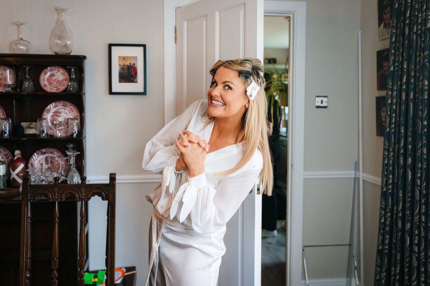 Person doing a joyful dancing pose in a bright room with decorative curtains and wall art. The Dean Dublin Wedding Photographer