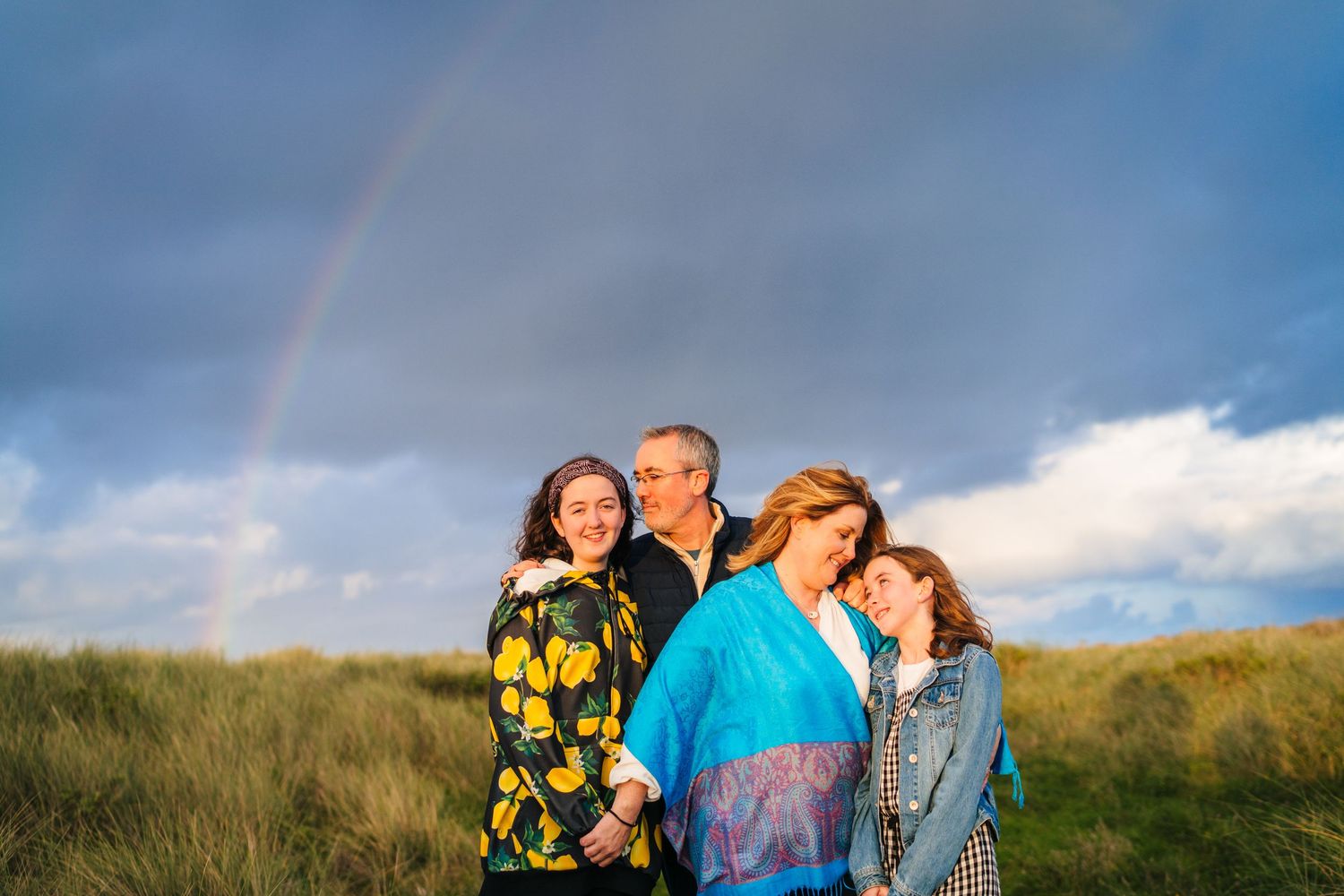 People walking together through a scenic mountainous landscape under dramatic cloudy skies. family PHOTOGRAPHER Dublin