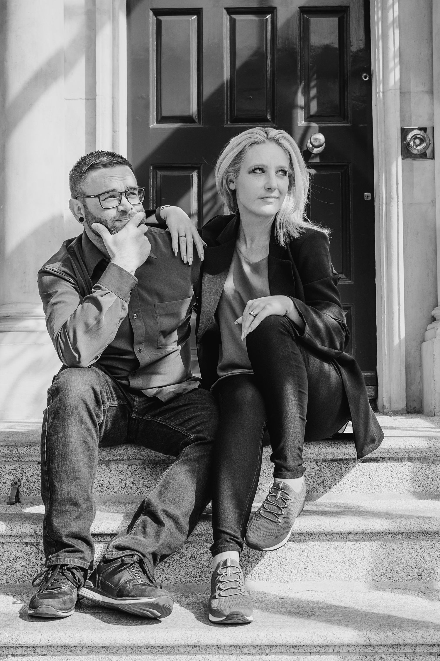 A black and white photograph shows two people sitting on steps outside a door in casual attire. PHOTOGRAPHER Dublin ireland