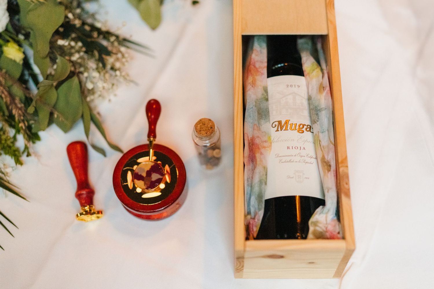 Wooden wine box and red serving items arranged on white surface with decorative greenery. Marco Pierre Dublin Wedding Photographer