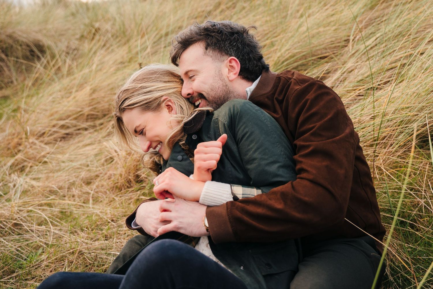 A playful and intimate moment shared between a couple laying in tall golden grass on an autumn day. PHOTOGRAPHER Dublin ireland