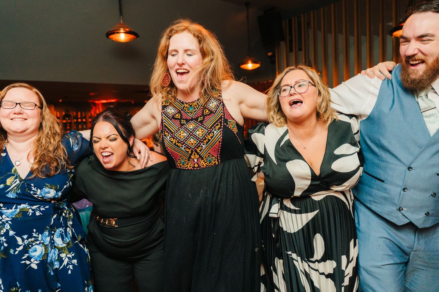 Wedding party dancing together in formal attire during an evening celebration.