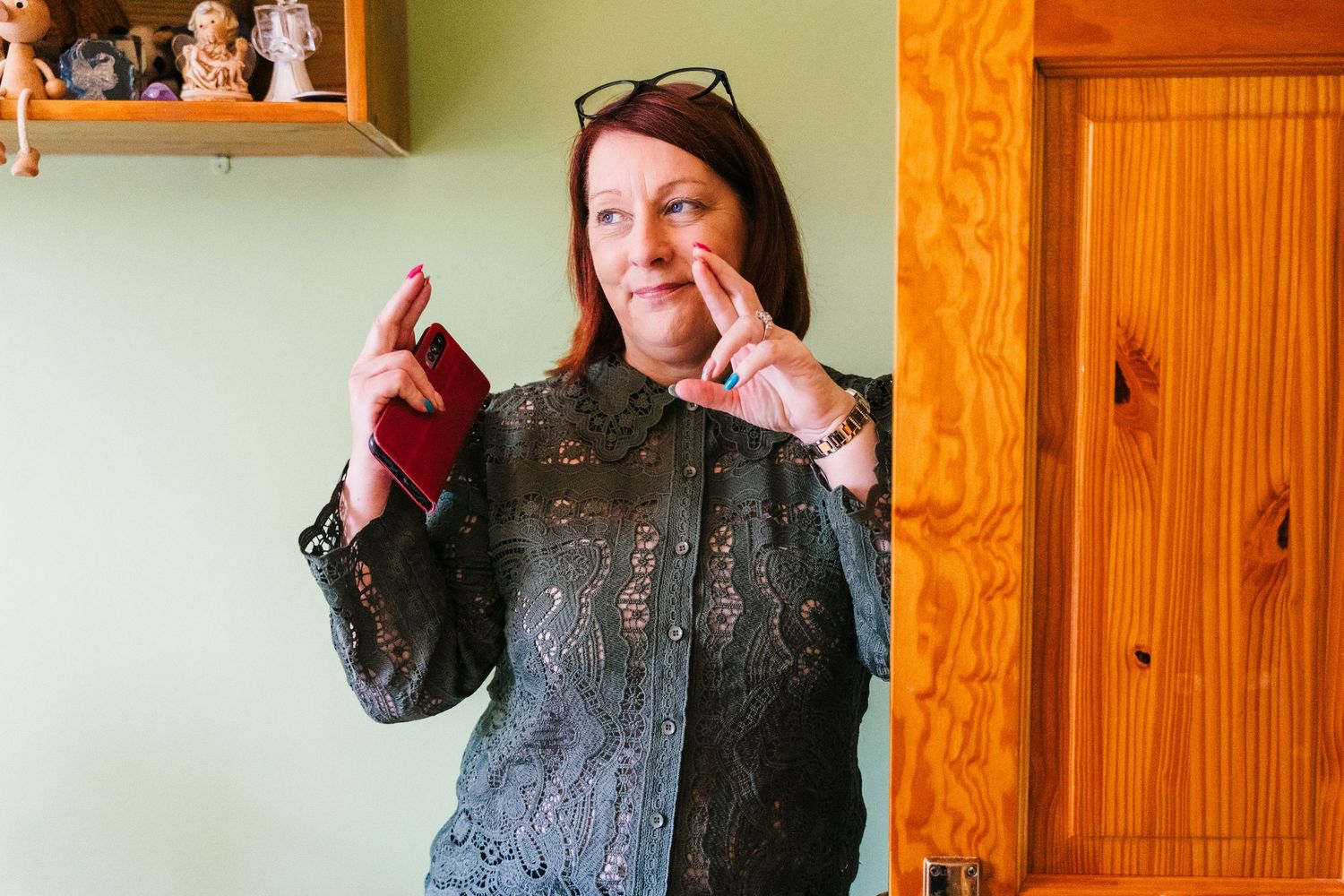 Millhouse slane wedding photographer dublin A woman wearing a black lace dress against a wooden paneled wall strikes a playful pose.