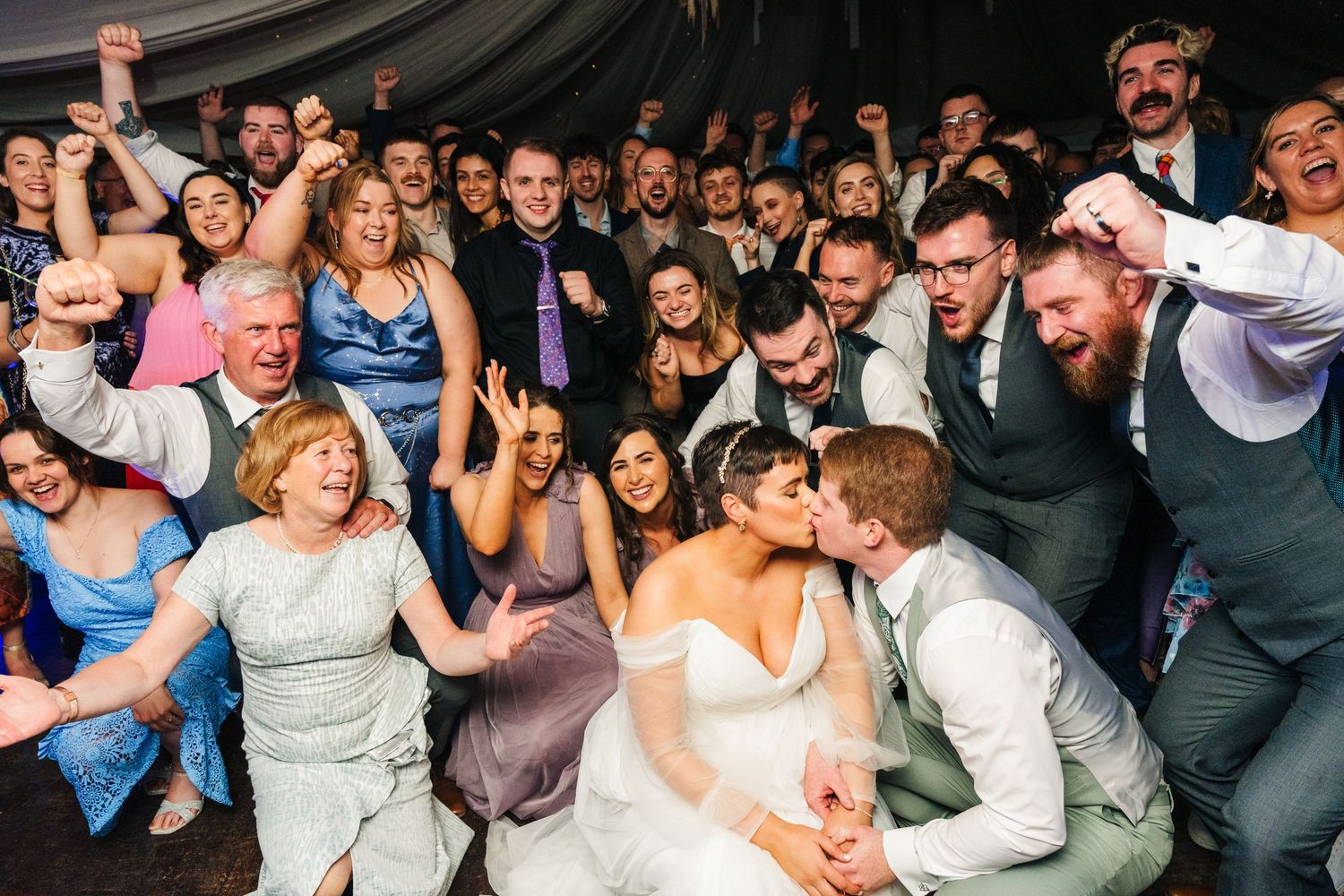 Millhouse slane wedding photographer dublin Large group of wedding guests celebrating enthusiastically on a dance floor.