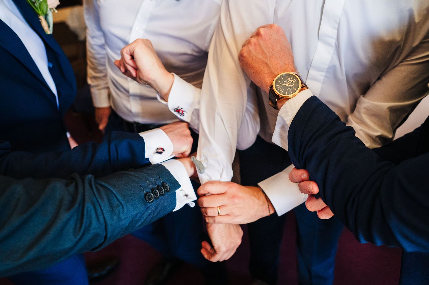 Groomsmen in suits adjust their cuffs and watch bands while preparing for a wedding ceremony. Castle Leslie Wedding Photographer Dublin