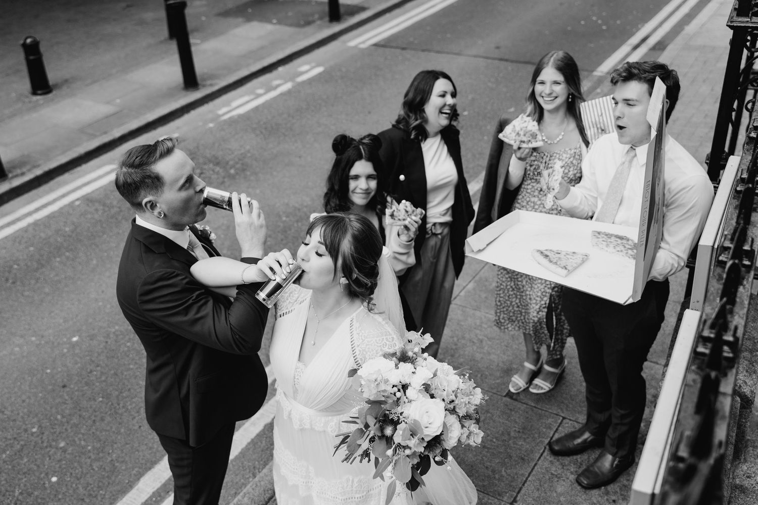 Wedding party celebrating on street with champagne and laughter. PHOTOGRAPHER Dublin Ireland Wedding