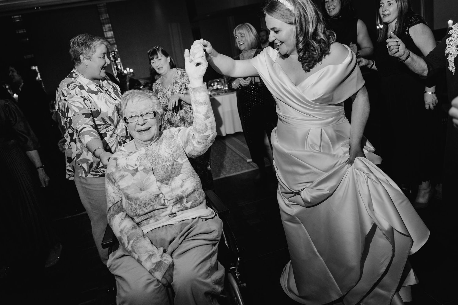 Wedding guests dancing and celebrating on a dimly lit dance floor.  Wedding PHOTOGRAPHER Trim Castle