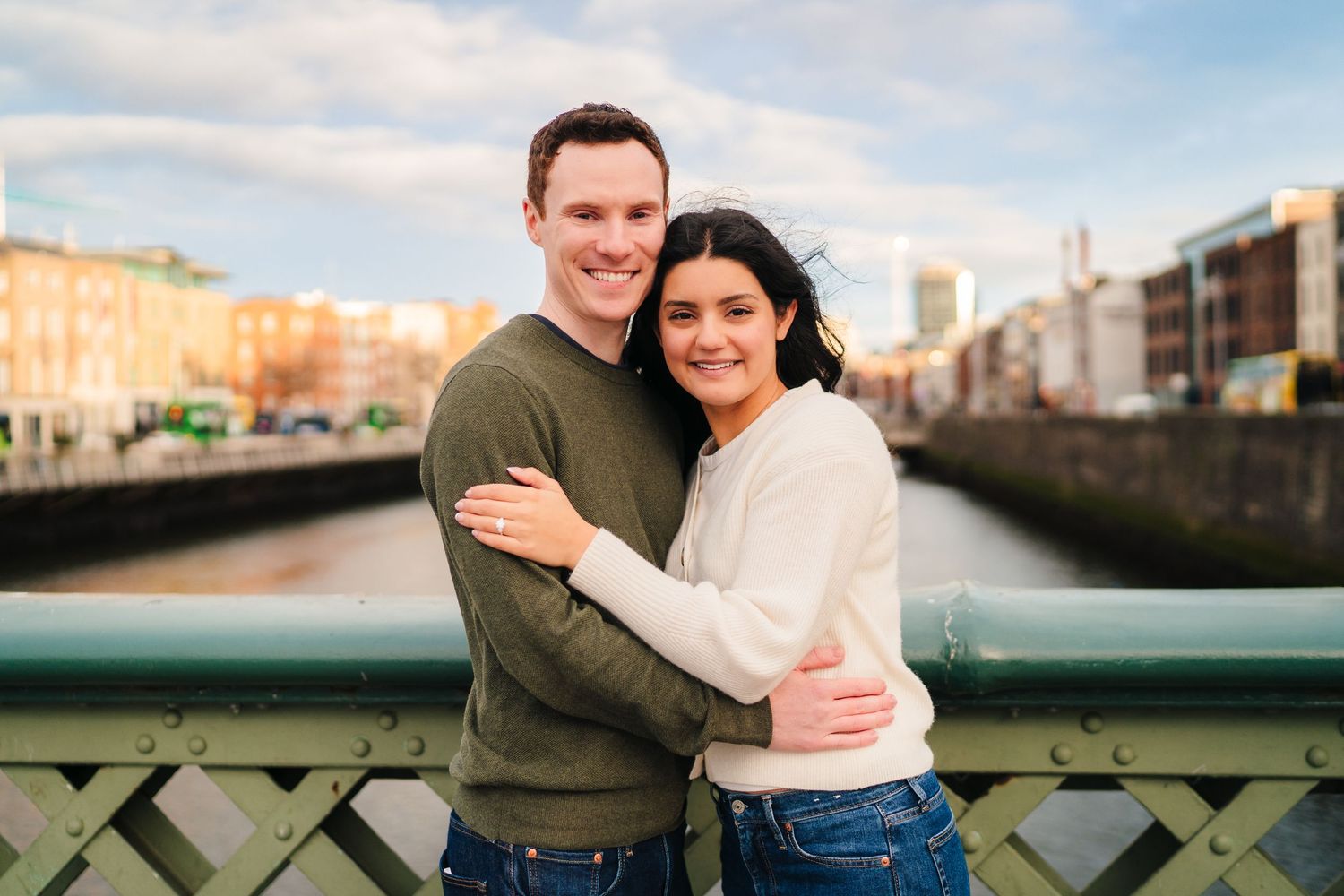 A couple poses together on a bridge over Dublin's River Liffey on a bright sunny day. Surprise proposal dublin photography