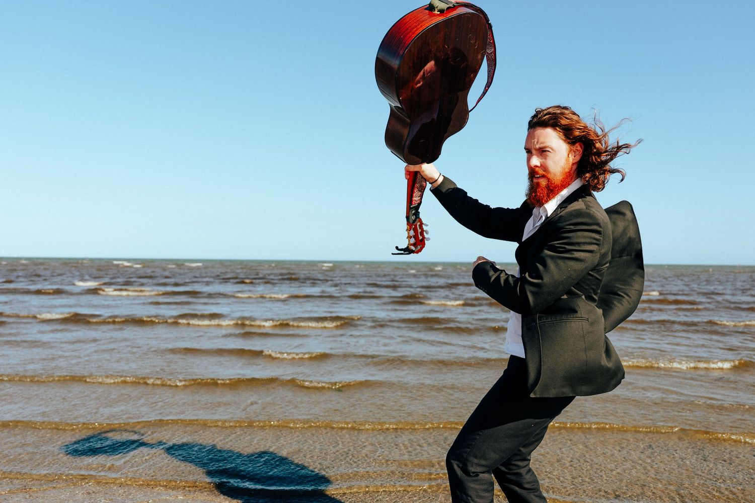 A sequence of playful jumping poses captured on a beach with water in the background. PHOTOGRAPHER Dublin