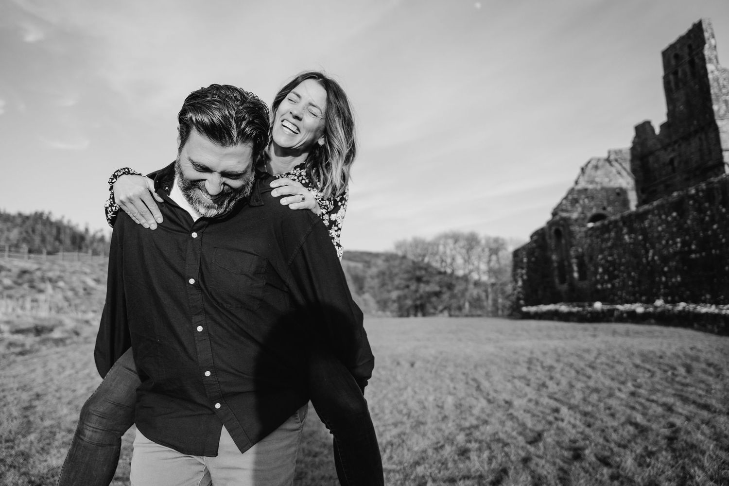 A joyful piggyback ride captured in black and white with scenic cliffs in the background. Photographer Ireland dublin