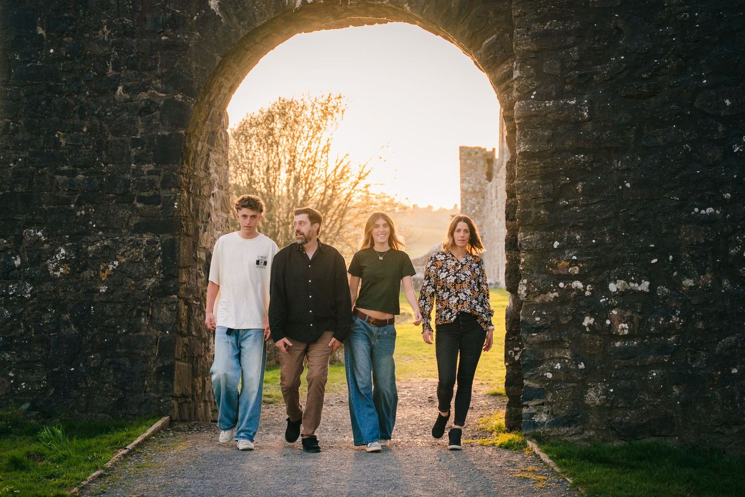 Four people walking through a stone archway during sunset. Photographer Ireland dublin