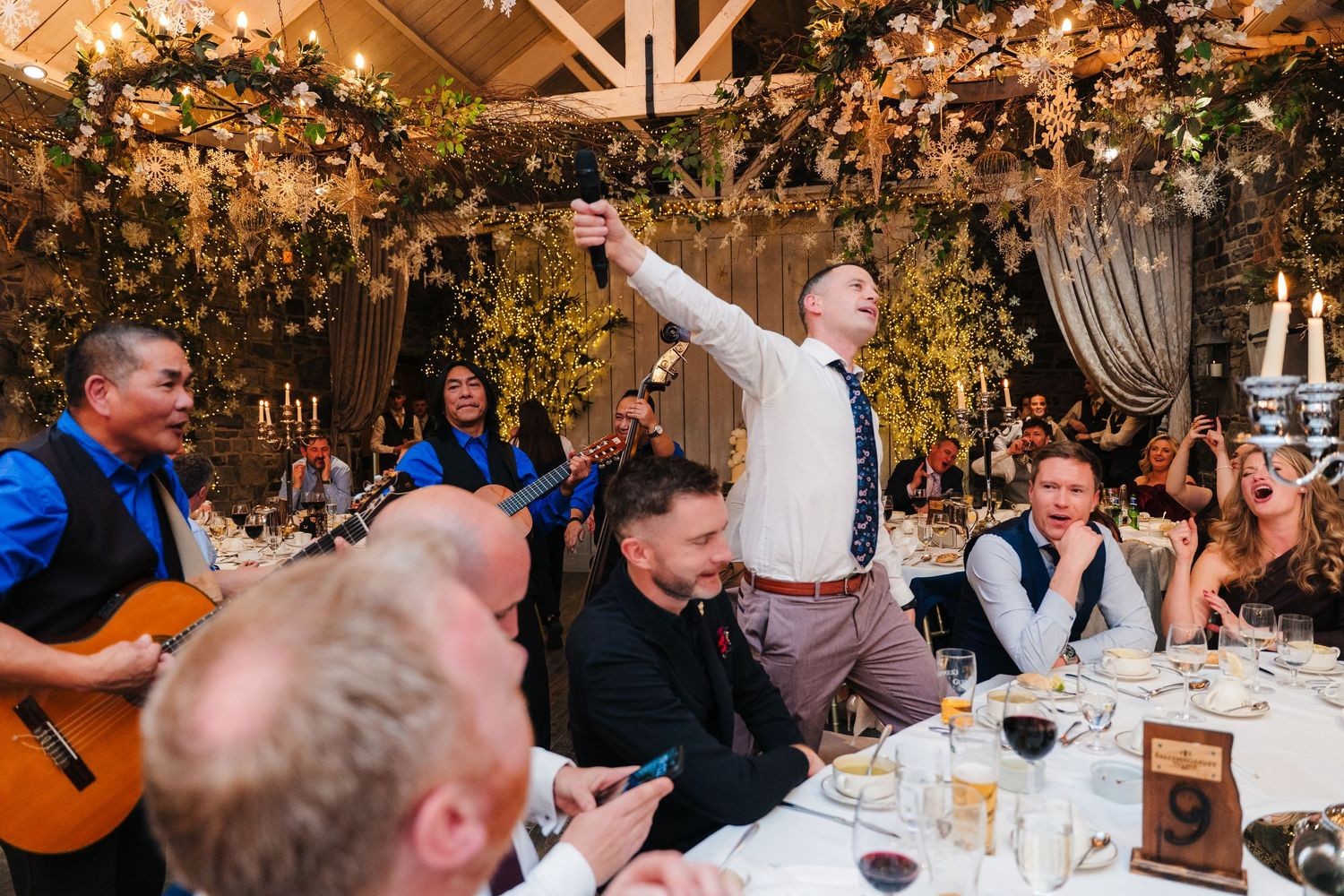 Guests celebrating at a wedding reception under warm lighting and decorative floral arrangements. Ballymagarvey Wedding photographer
