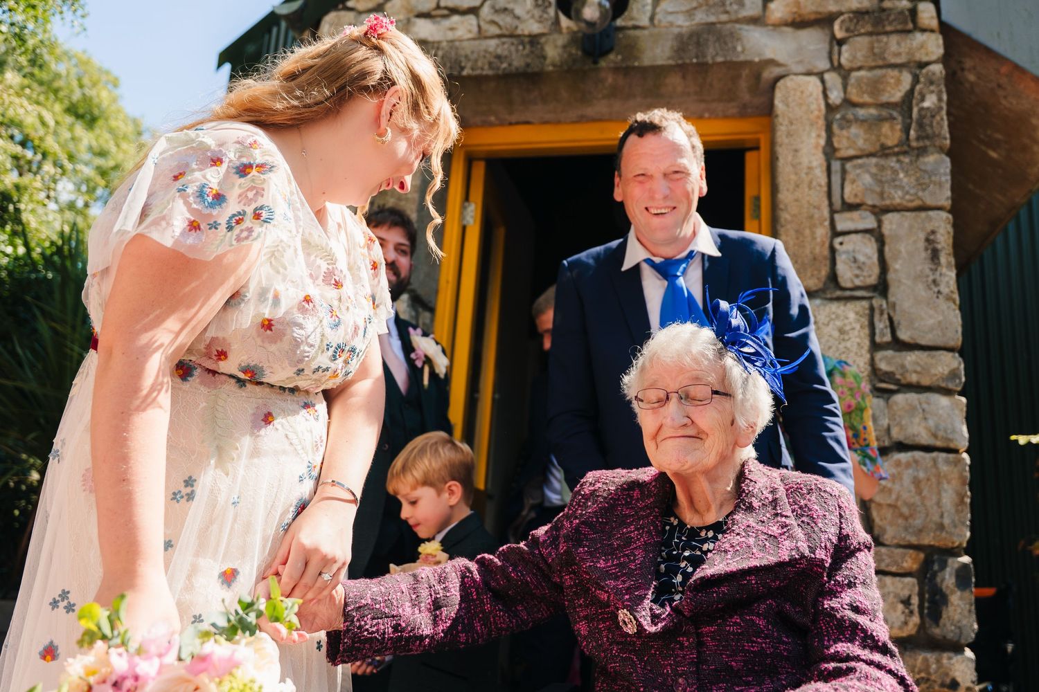 Wedding guests gathered outside a rustic stone building on a sunny day. Wedding Photographer Dublin Ireland
