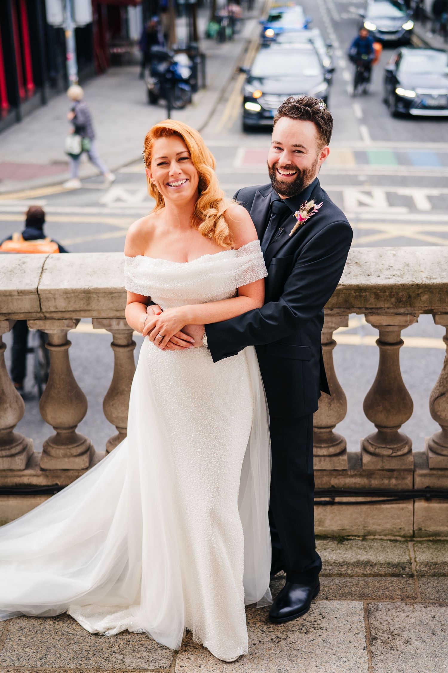 Wedding couple poses along stone balustrades in an urban setting with flowing white dress.  city hall dublin wedding photos