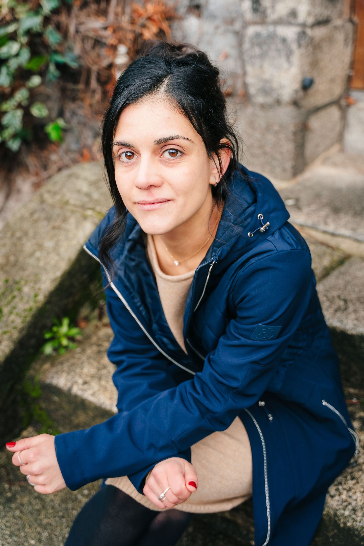 A person in a navy blue jacket sits on concrete steps while looking upward in a series of similar poses. professional headshots dublin