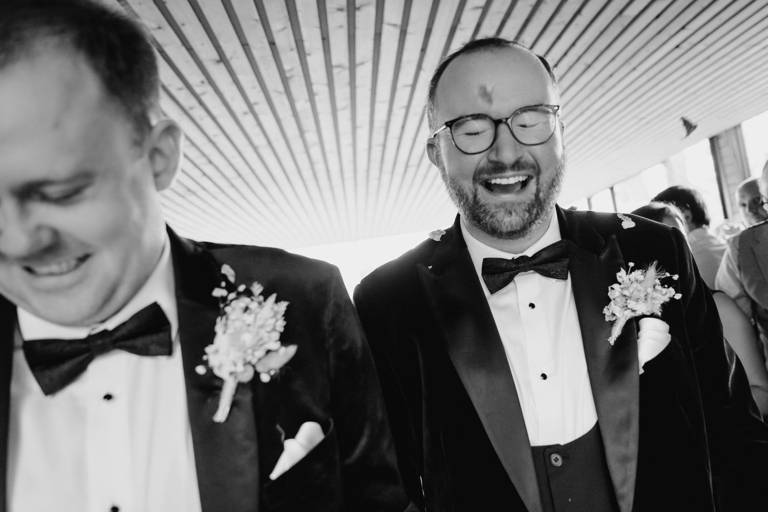 A group of people in formal black and white attire laughing and smiling at a celebratory event. wedding photographer dublin pricing meath